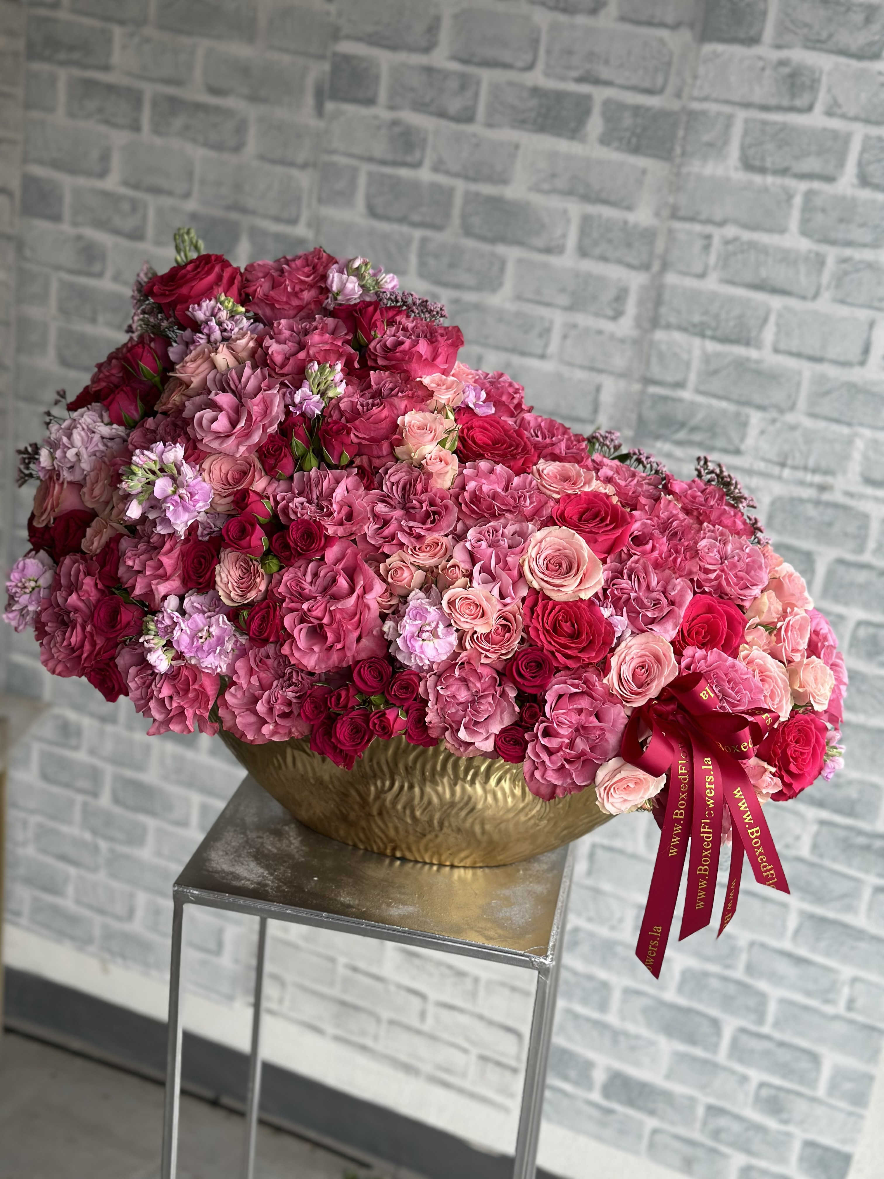 Large pink and red rose arrangement in a gold bowl