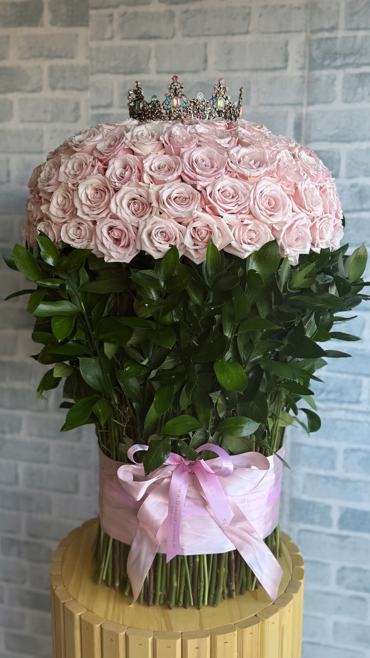 Large pink rose arrangement topped with a jeweled crown