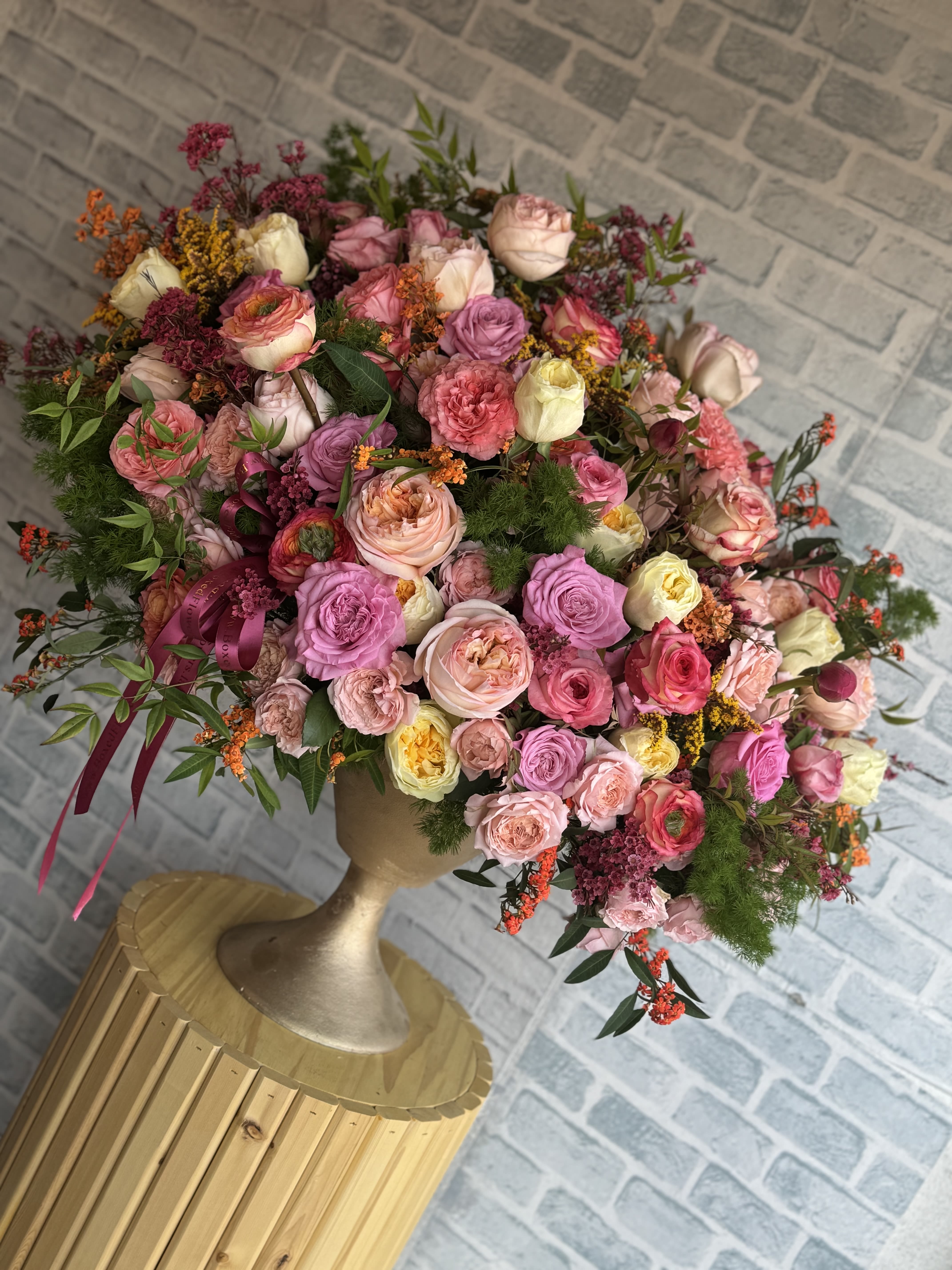 Large bouquet of pink and cream roses in a gold vase