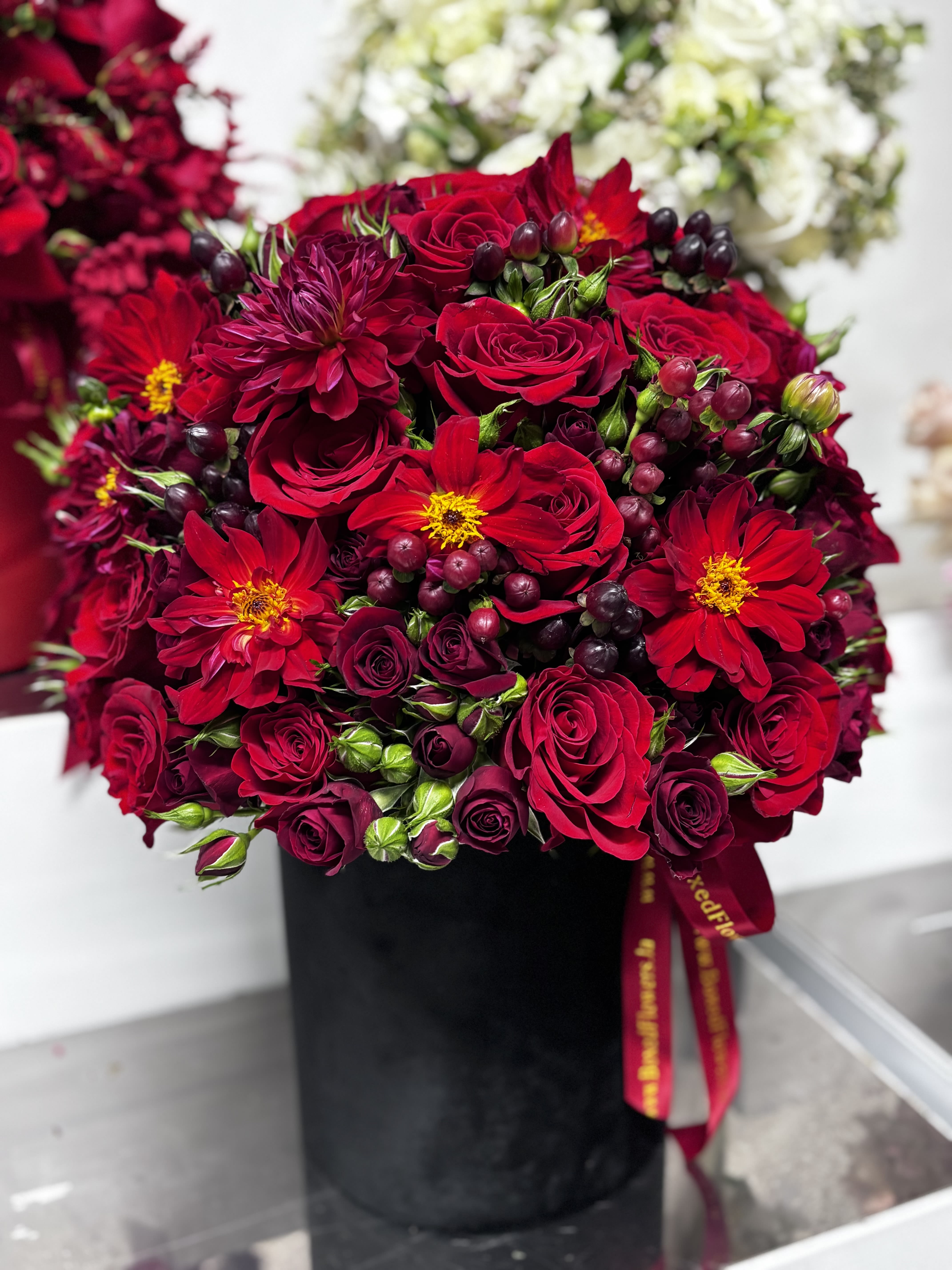 Red roses and burgundy flowers arranged in a black box