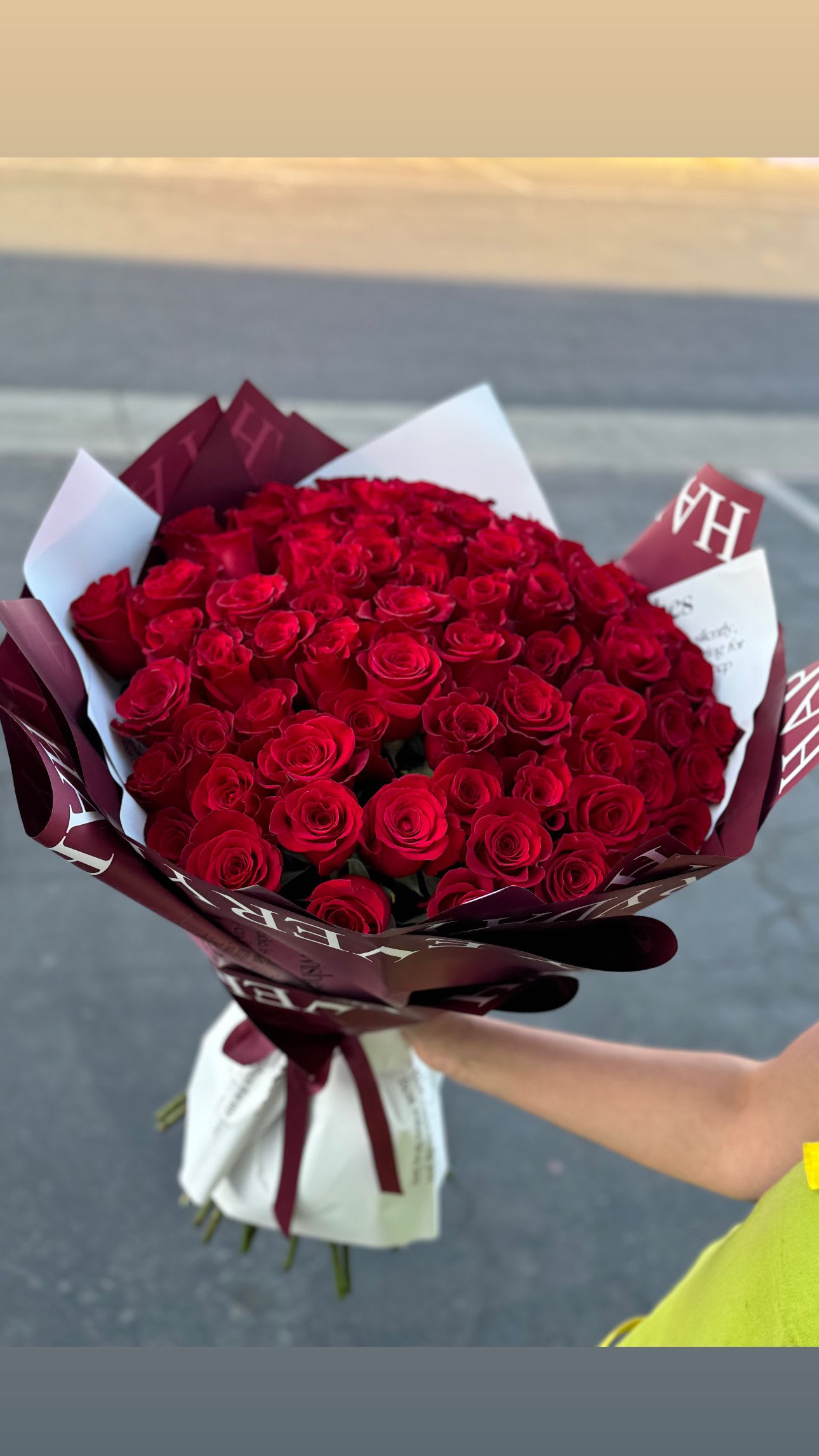 Large bouquet of red roses wrapped in burgundy and white paper