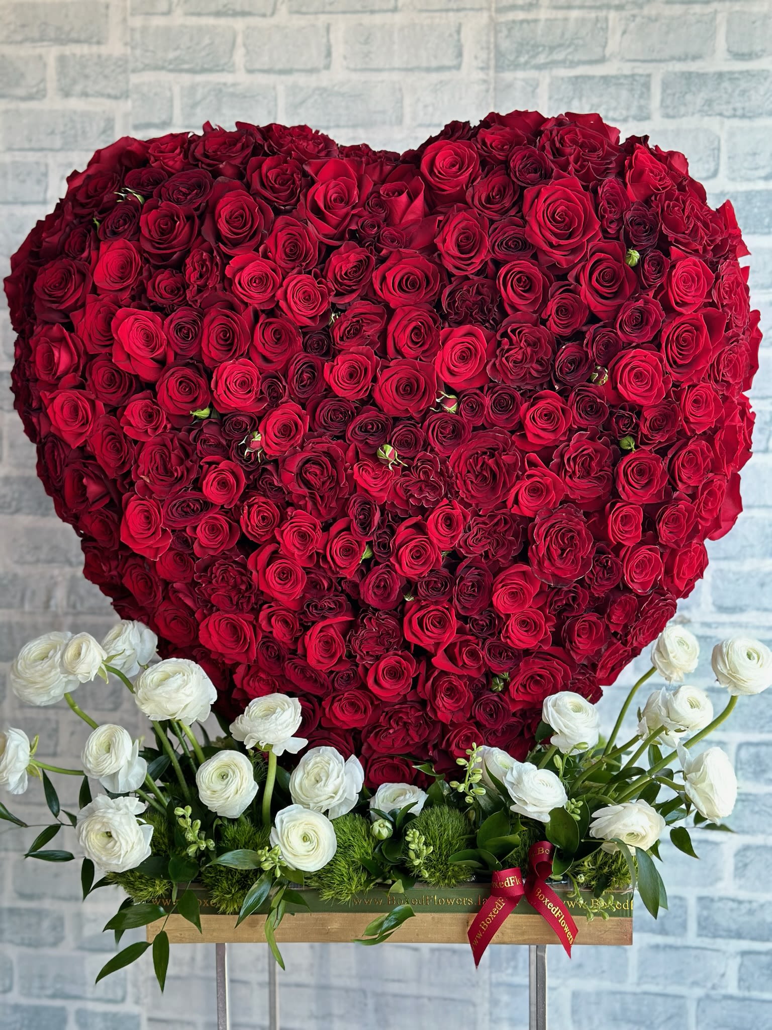 Heart-shaped red rose arrangement with white flowers at the base