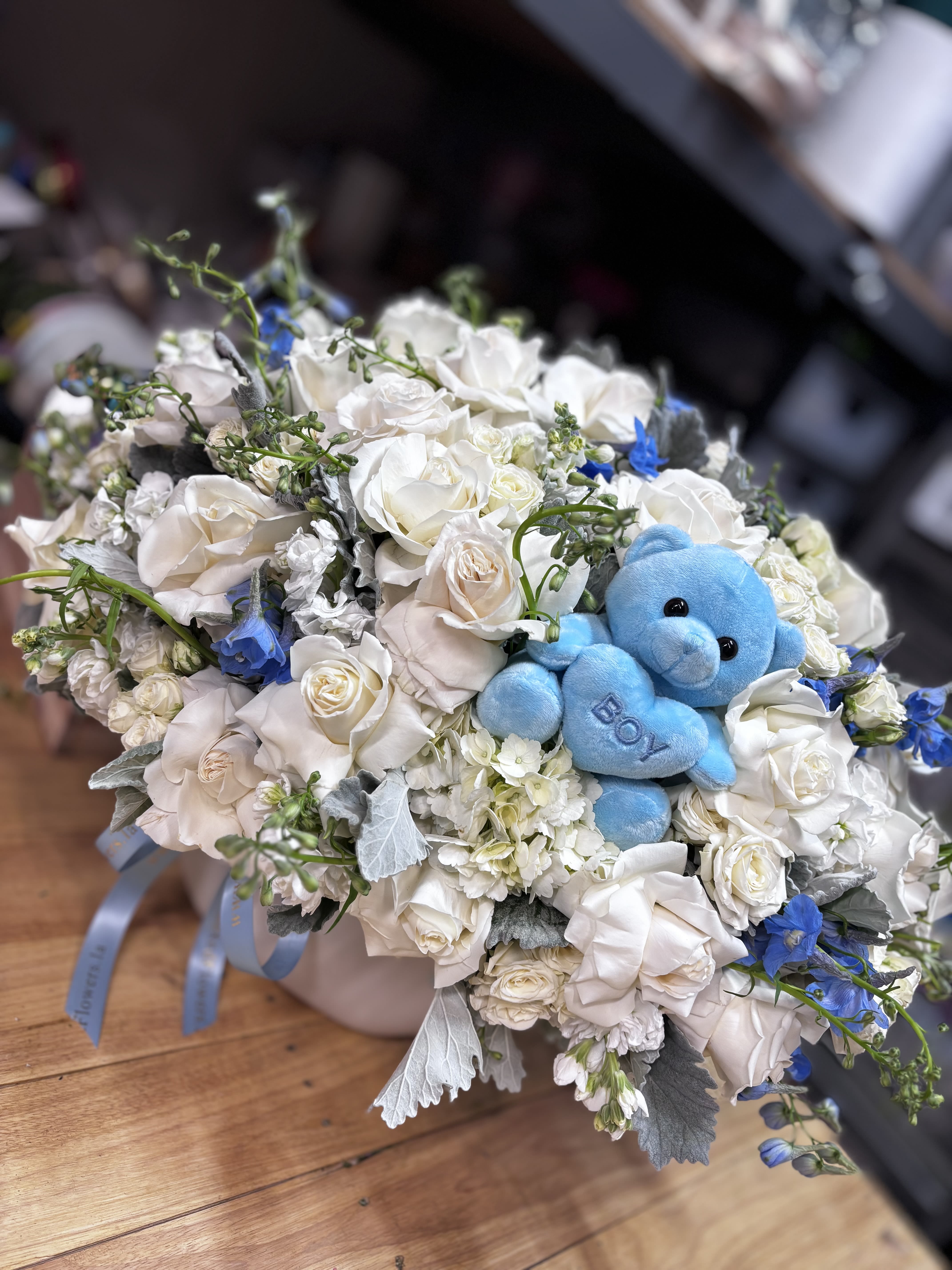 White rose bouquet with a blue teddy bear in the center