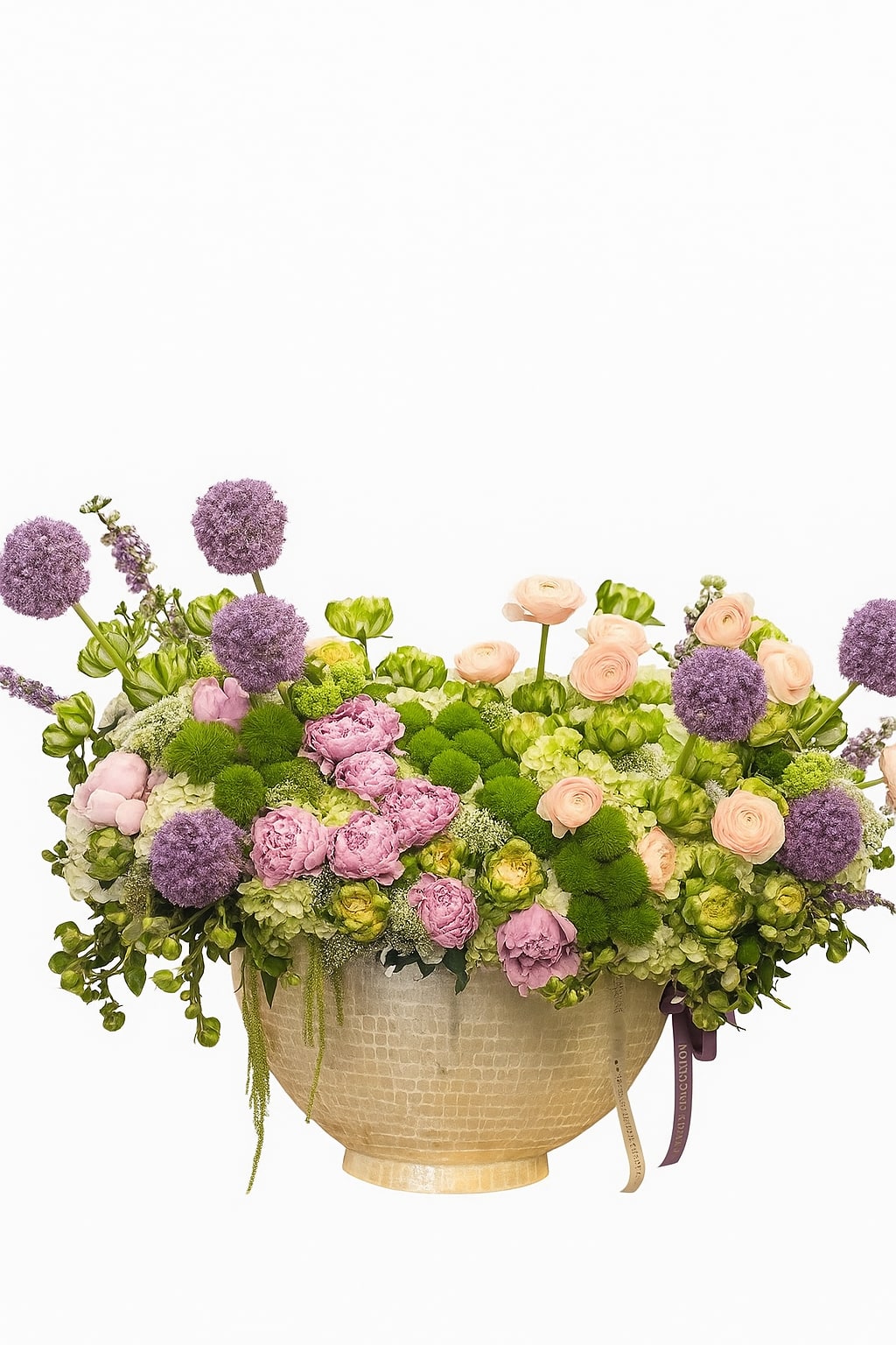 Spring Sonata - A lavish garden-inspired arrangement overflowing with seasonal beauty, Spring Sonata blends soft pastels and rich textures into one harmonious composition. Featuring lush pink peonies, creamy ranunculus, vibrant green hydrangeas, mossy accents, and whimsical purple alliums, this bouquet is housed in an elegant, hammered ivory vase with a satin ribbon finish. The arrangement’s airy, organic form evokes a sense of freshness, growth, and natural grace—perfect for spring celebrations, elegant events, or heartfelt gifts.