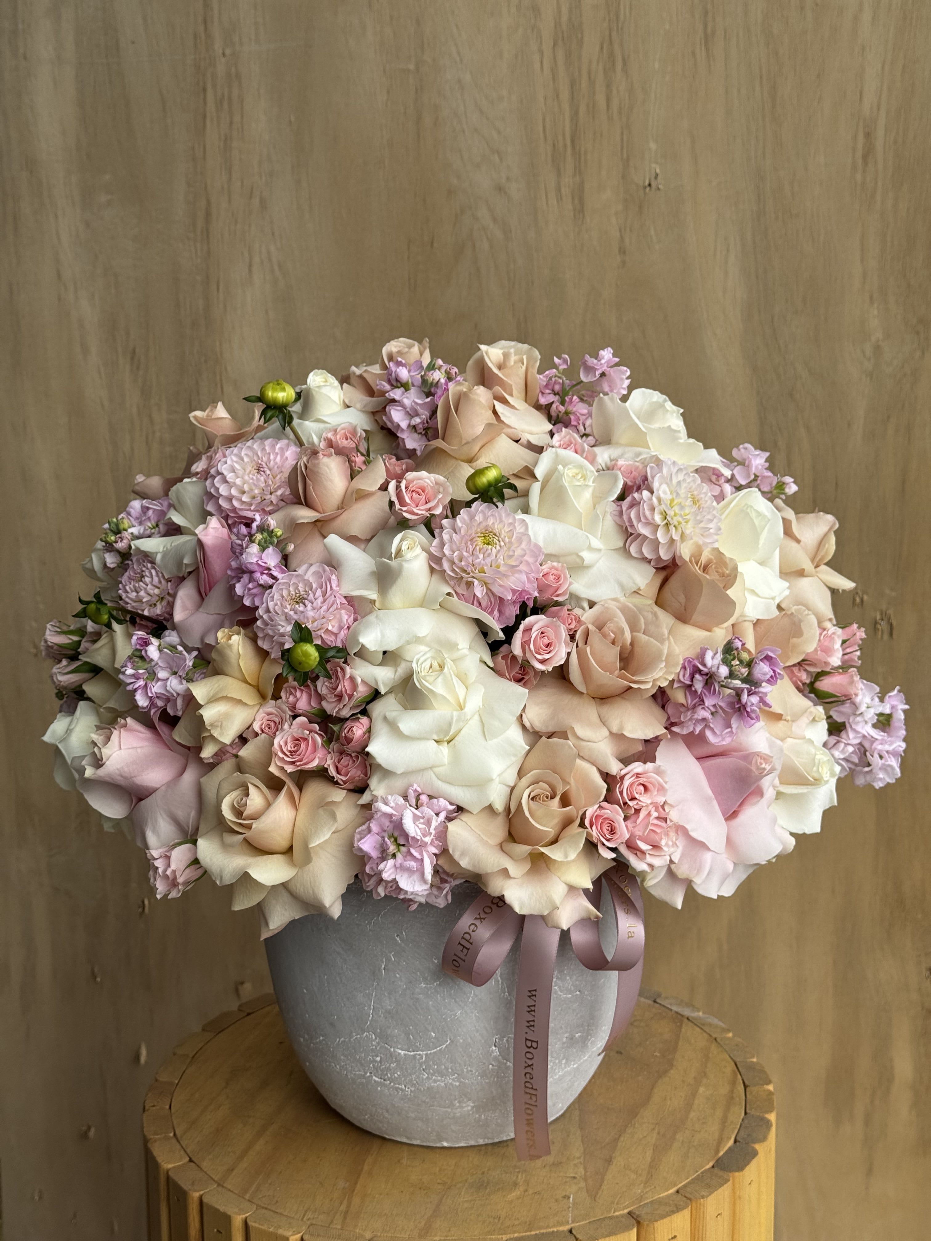 Large pastel bouquet of roses, chrysanthemums, and small pink flowers in a gray vase