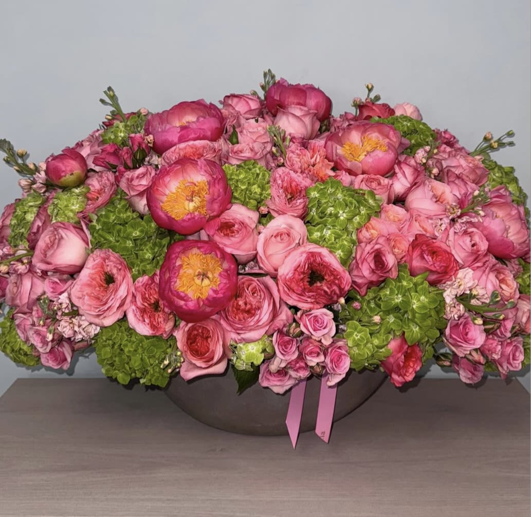 Pink floral arrangement with roses and peonies in a low bowl
