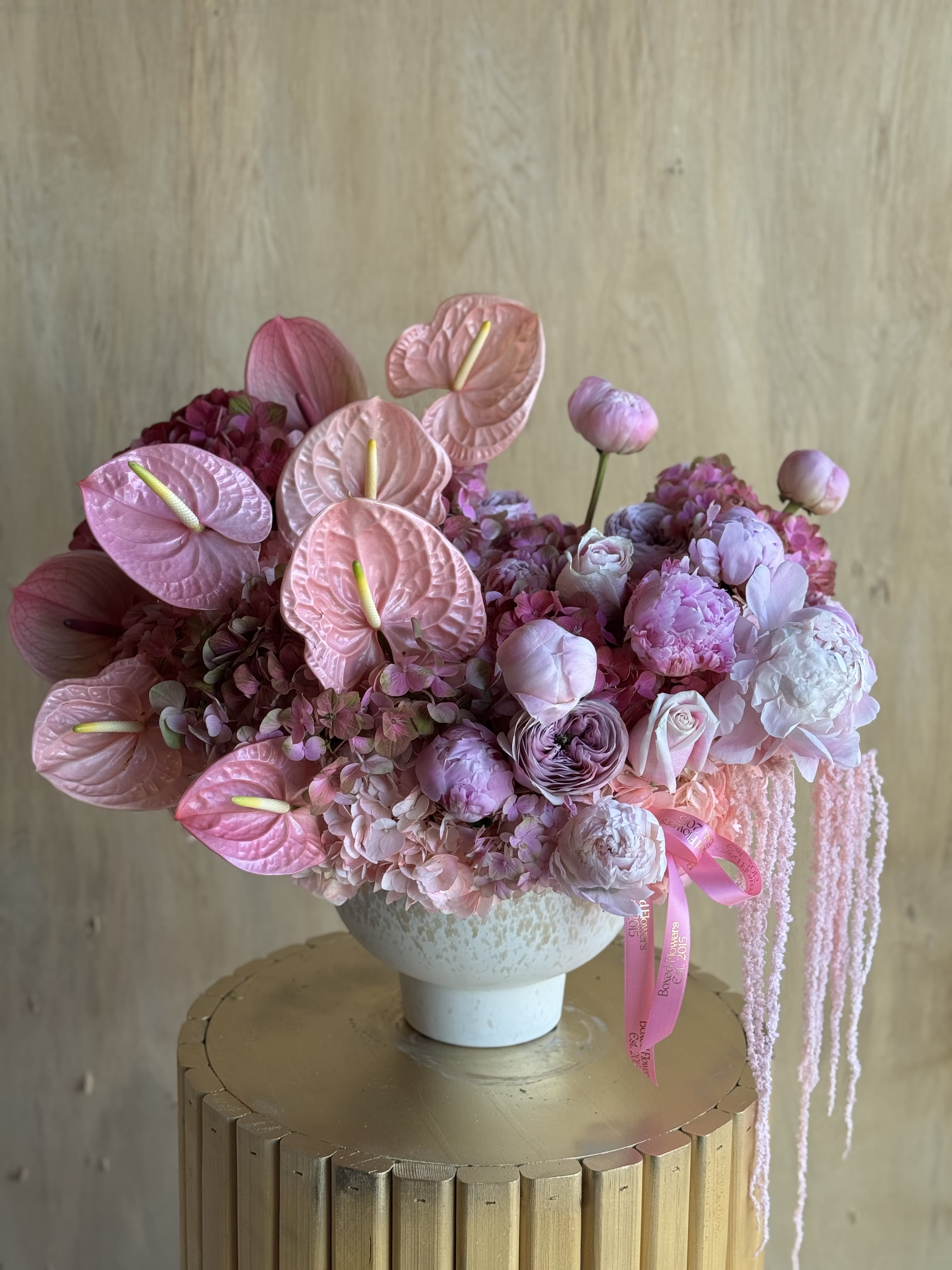 Pink floral arrangement in a white vase with anthuriums and peonies