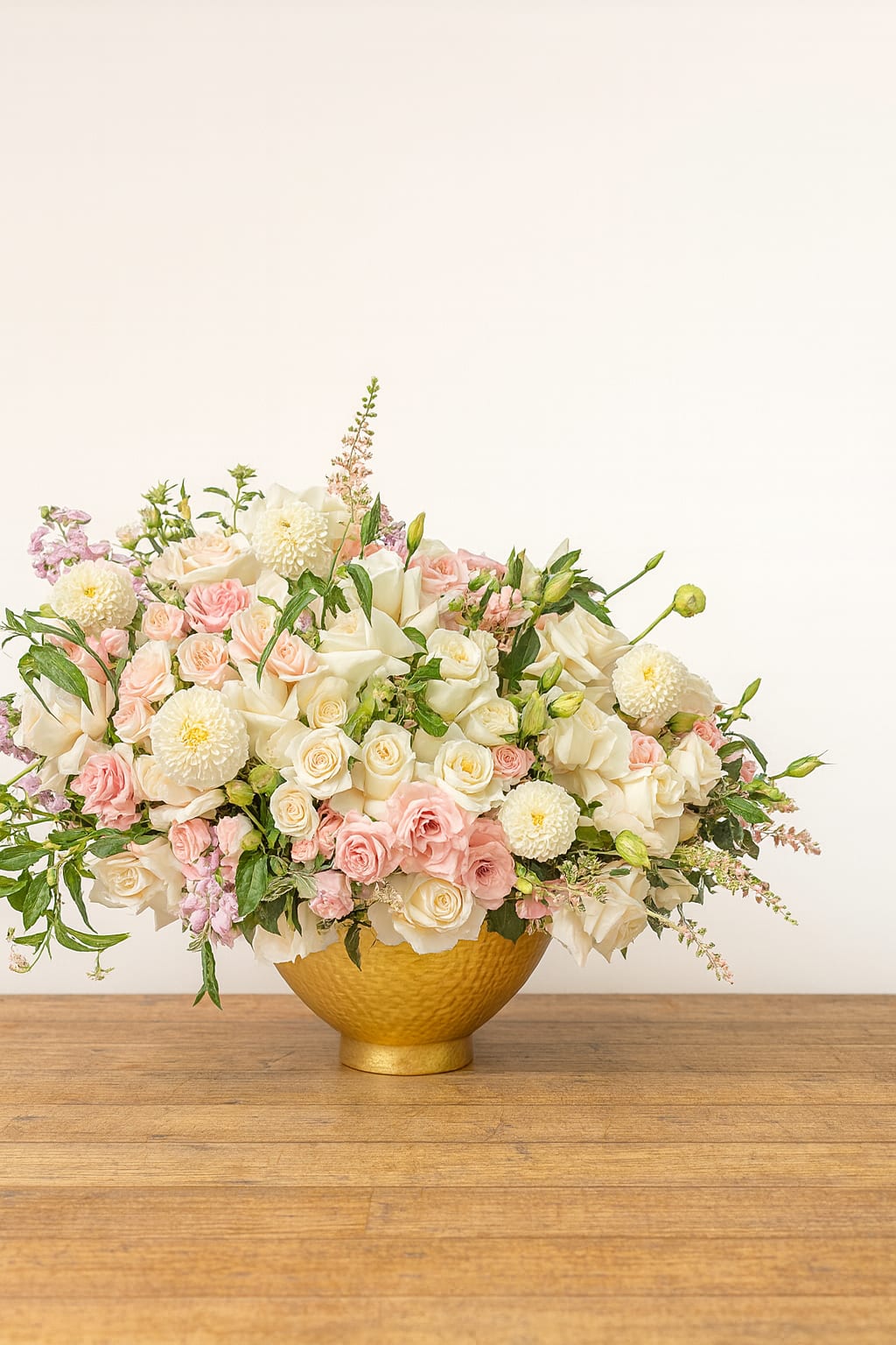 Blush and white rose arrangement in a gold bowl vase