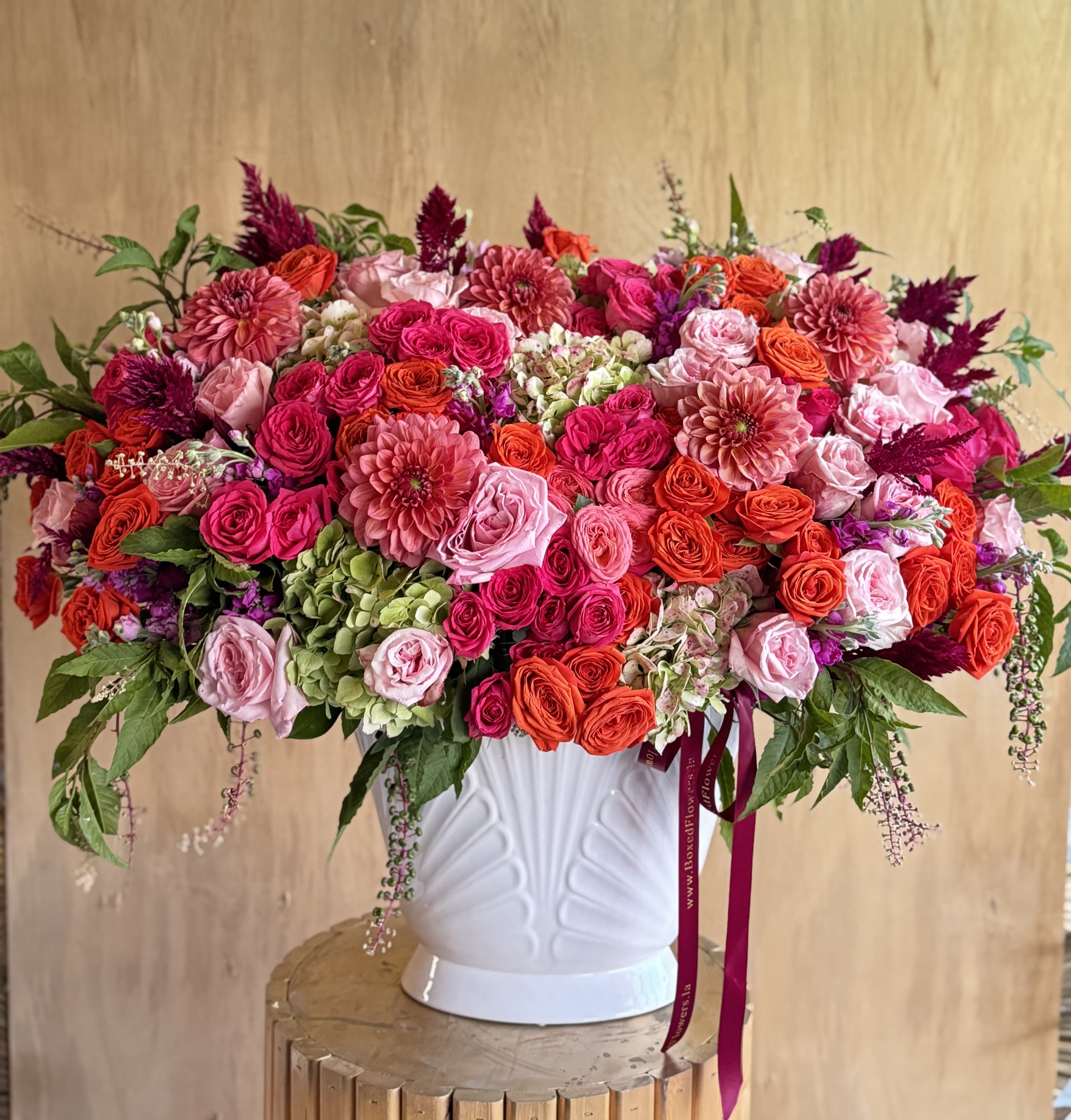 Large pink and orange floral arrangement in a white vase