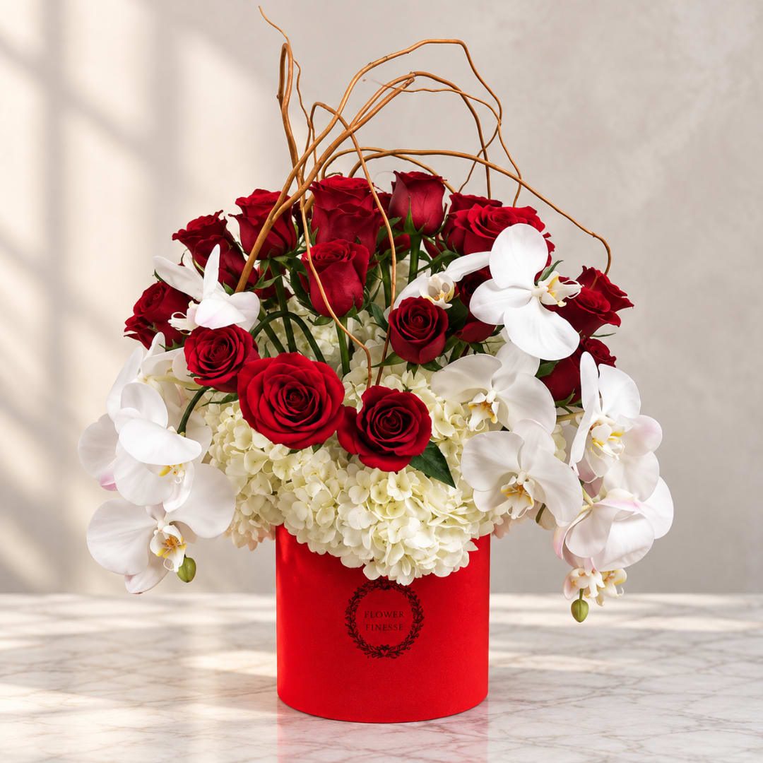 Red roses and white orchids arranged in a red box with curly branches