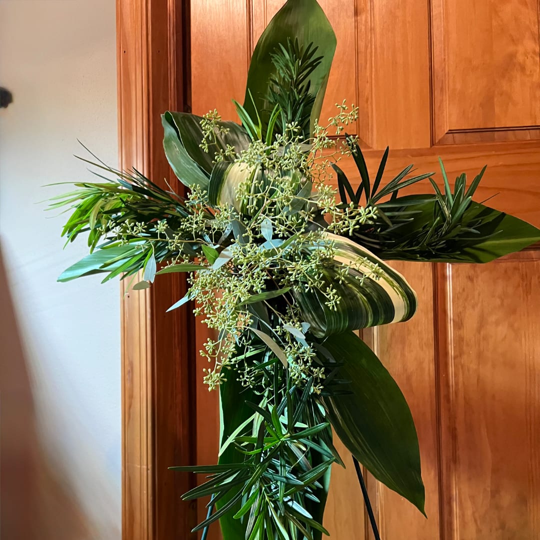 Tall green floral arrangement with broad leaves and cascading greenery