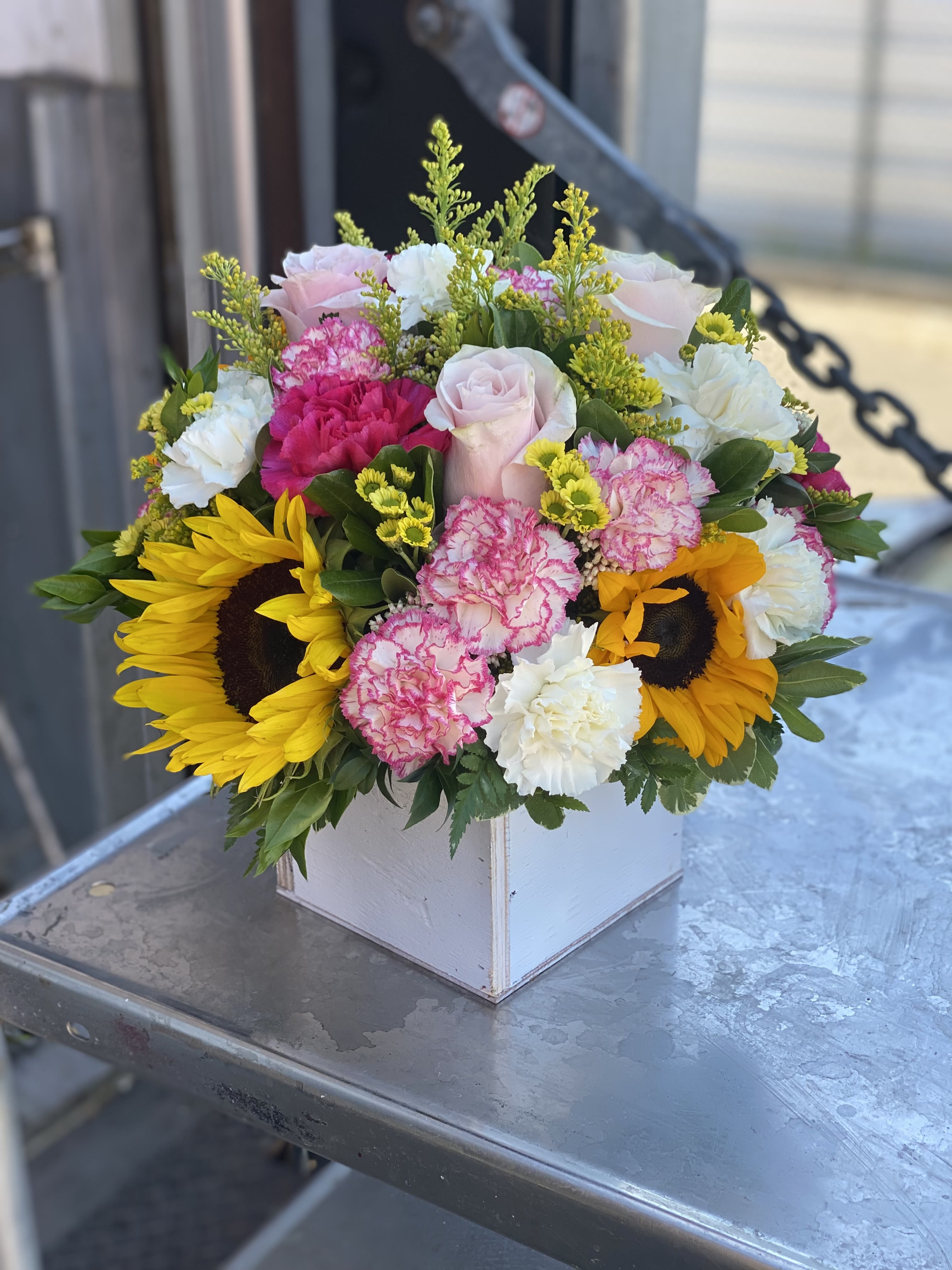 Mixed bouquet with sunflowers, pink roses, and carnations in a white box