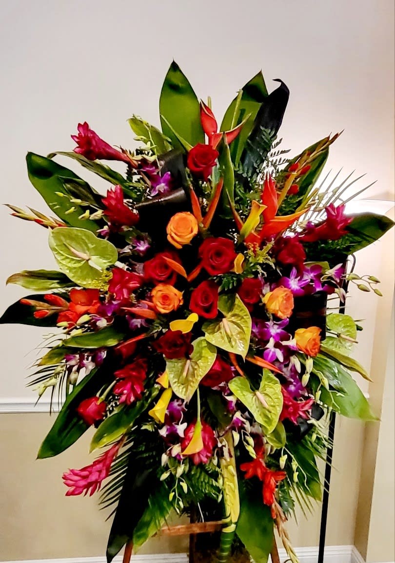 Large tropical floral arrangement with red and orange roses in a stand