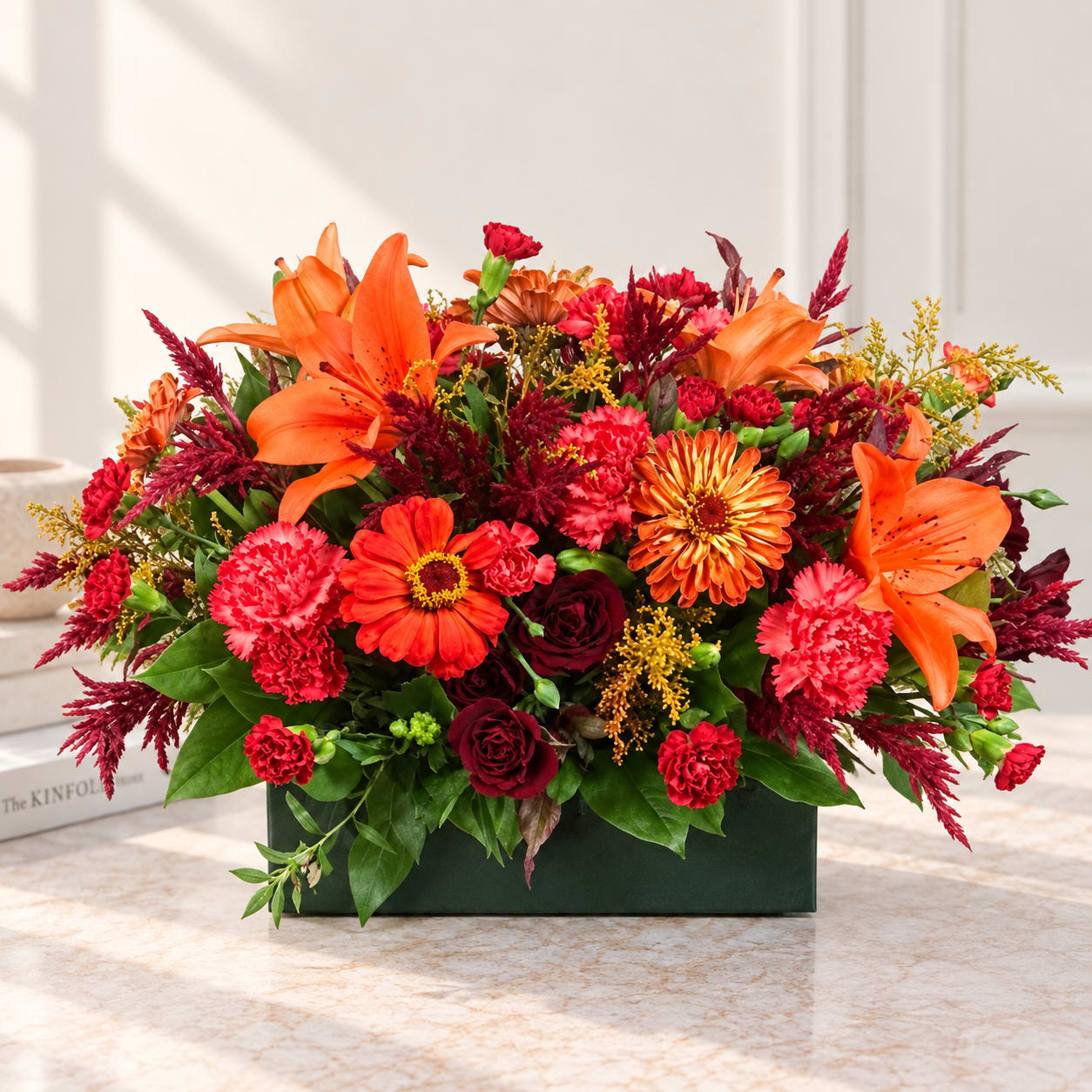 Orange lilies and red mixed flowers arranged in a dark green box