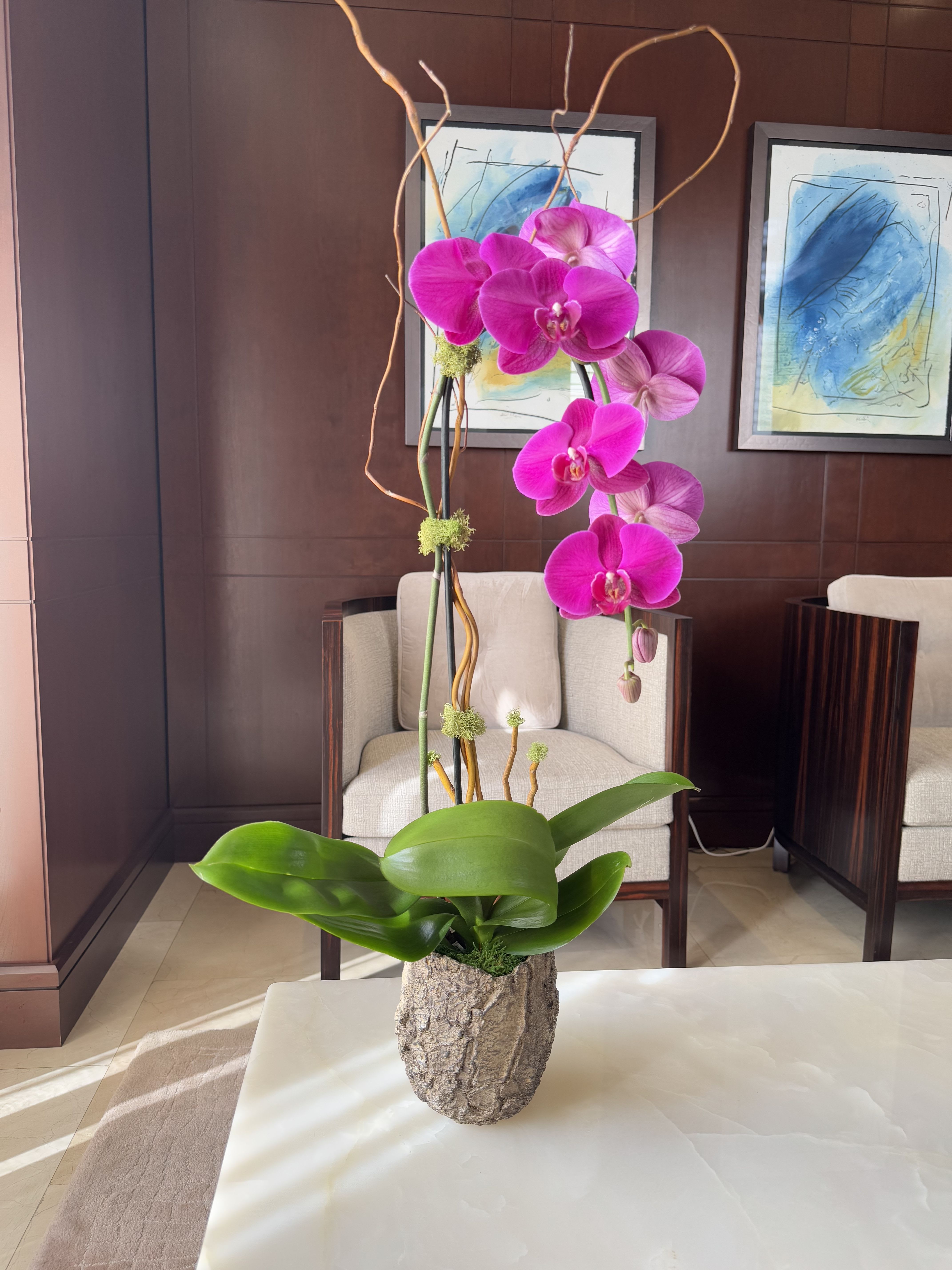 Tall orchid arrangement in a textured stone vase