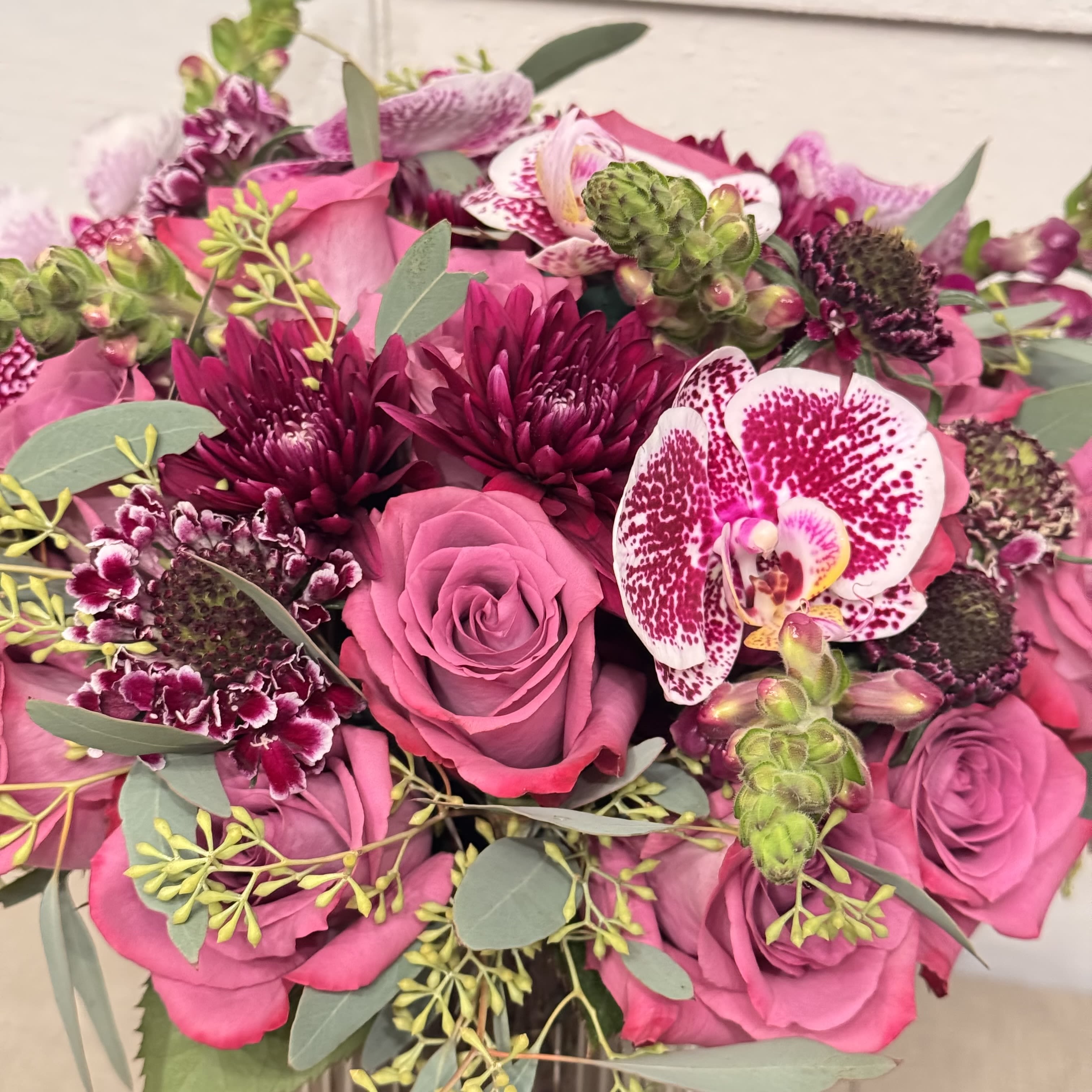 Pink roses and orchids with dark burgundy blooms in a bouquet