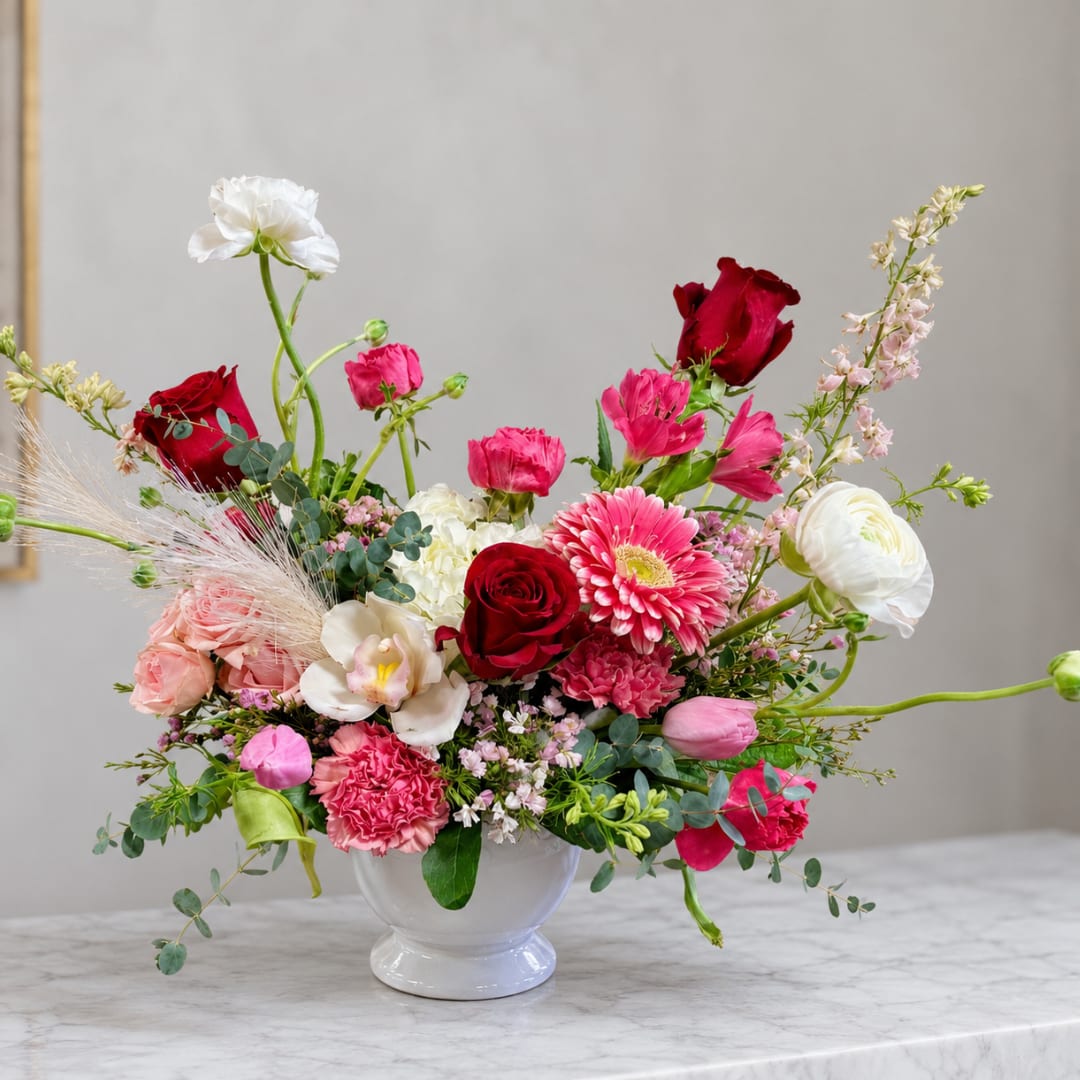 Mixed pink and red flower arrangement in a white vase