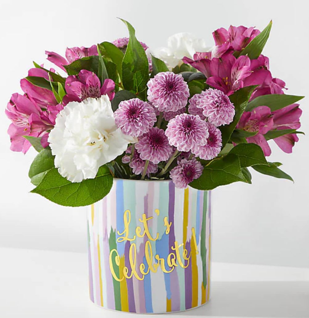 Pink and white flower arrangement in a striped vase with "Let's Celebrate" text