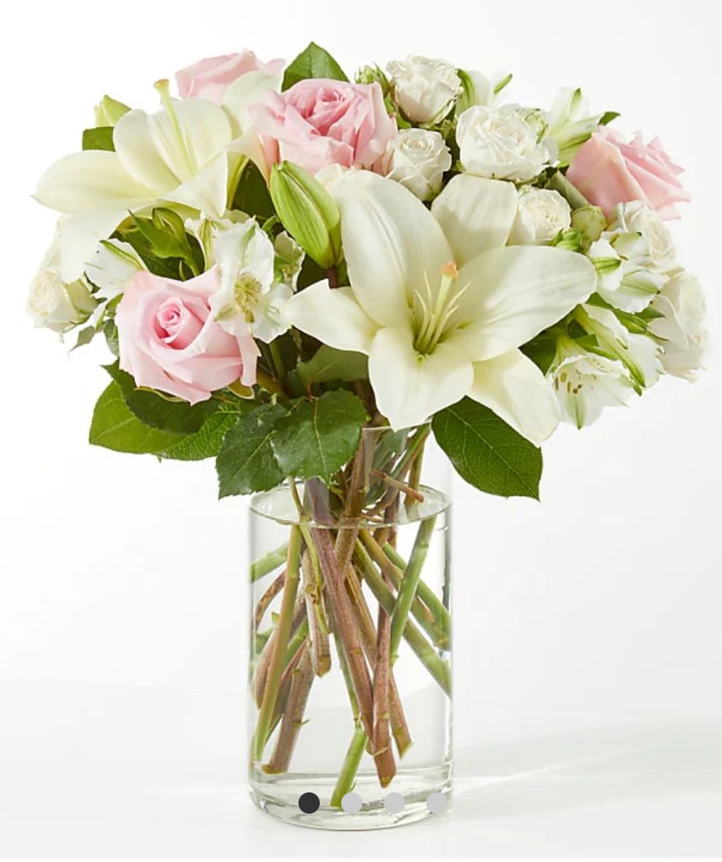Pink and white bouquet of roses and lilies in a clear glass vase