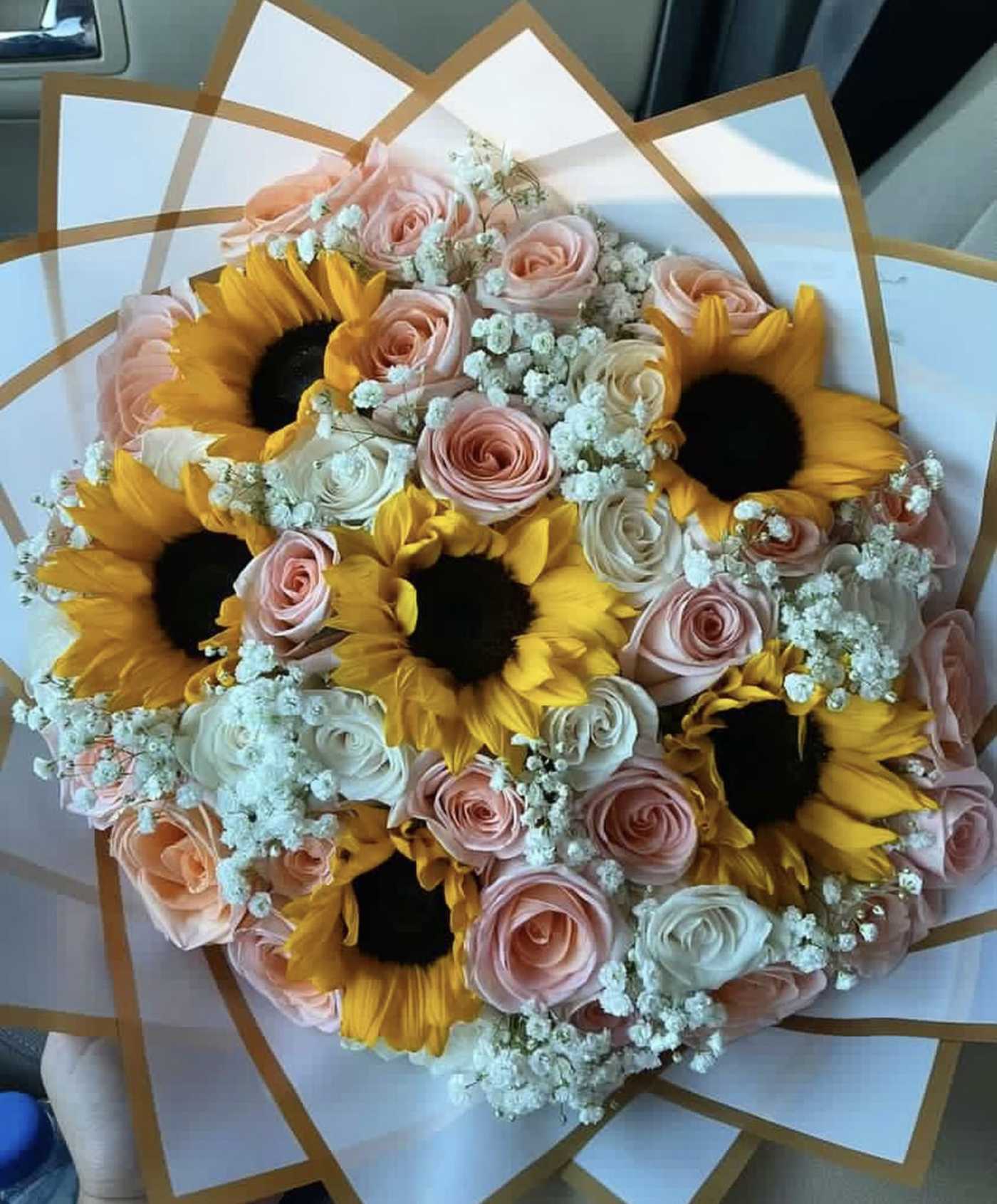 Bouquet of sunflowers, pink roses, and baby's breath in white wrap