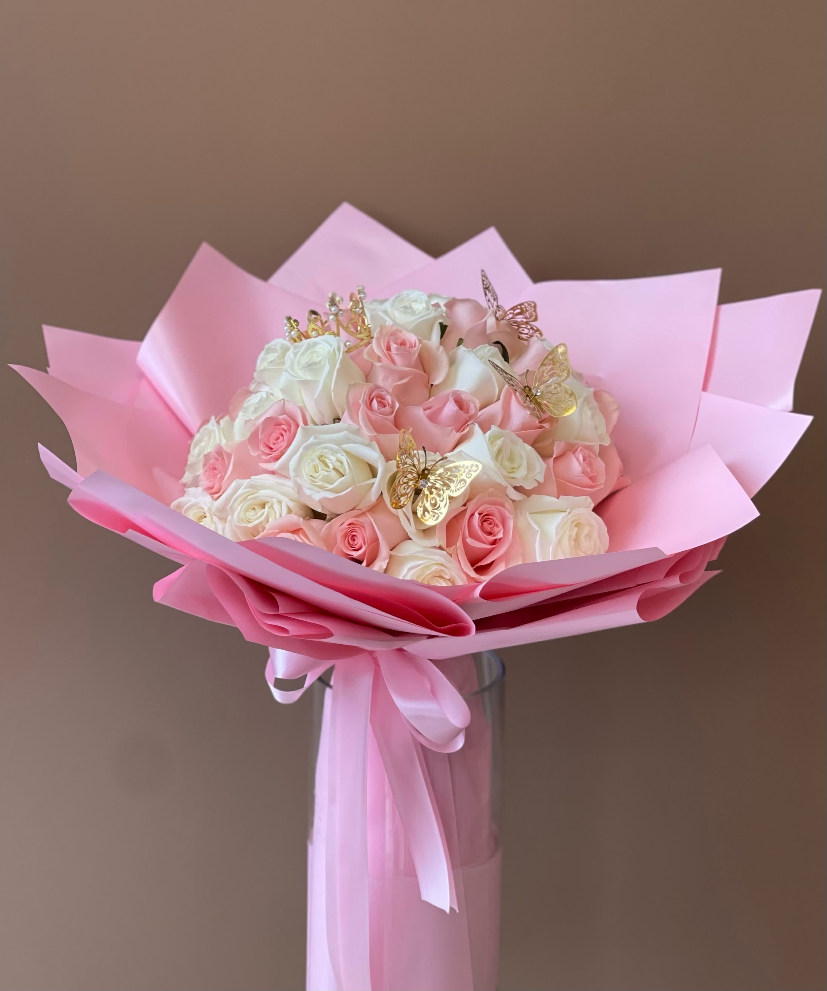 Pink and white rose bouquet wrapped in pink paper with butterfly picks