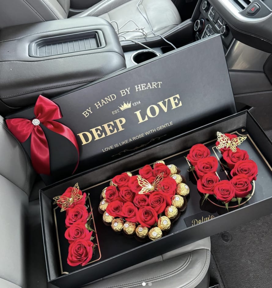Red roses and chocolates arranged in a black gift box with a ribbon