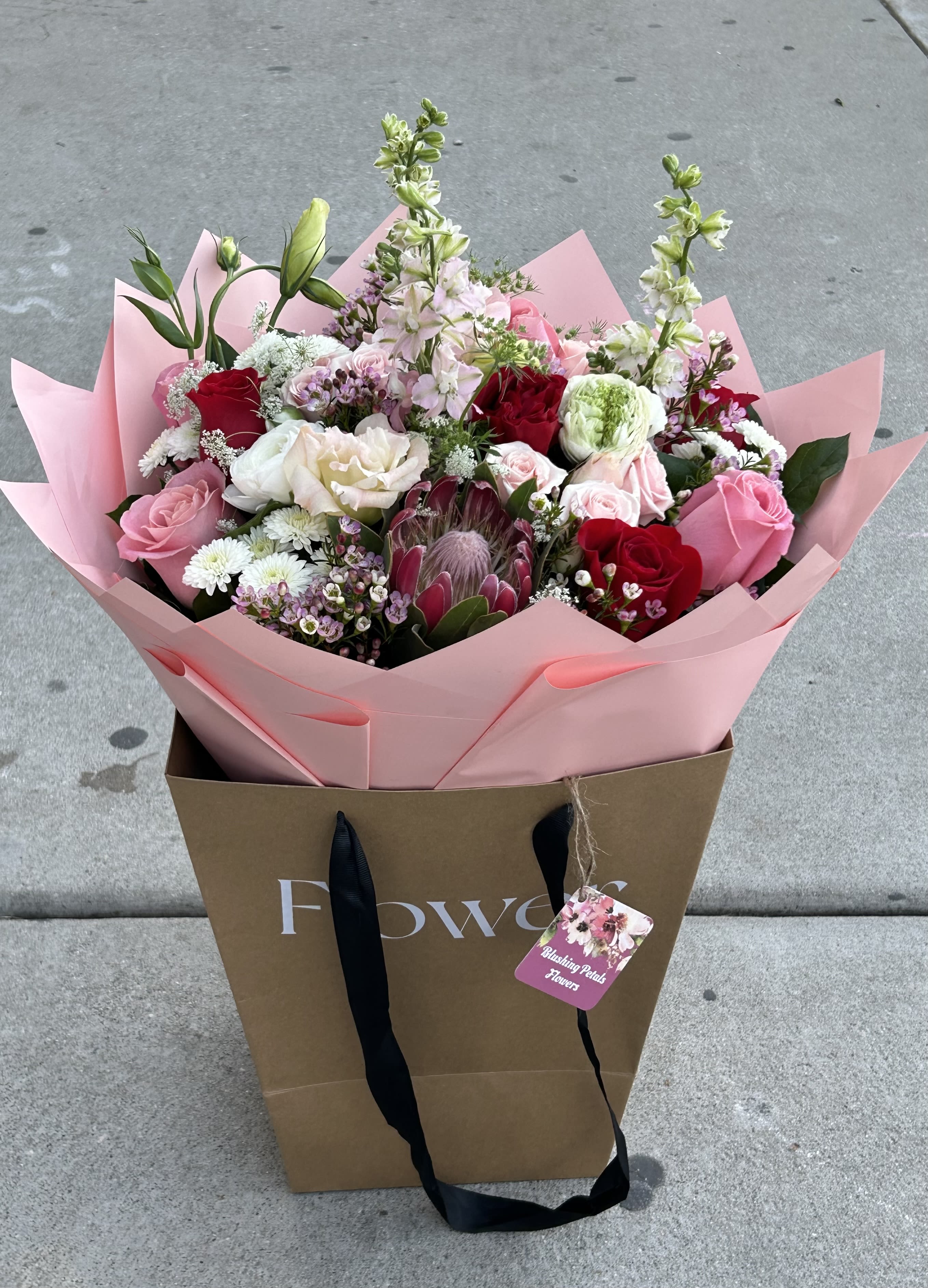 Mixed bouquet of pink, red, and white flowers in pink wrap