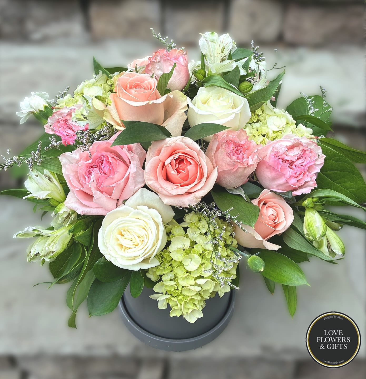 Austen  - Designed in a slightly tall grey ceramic pot made with soft light pinks, creams and greens for a elegant yet unique look. 