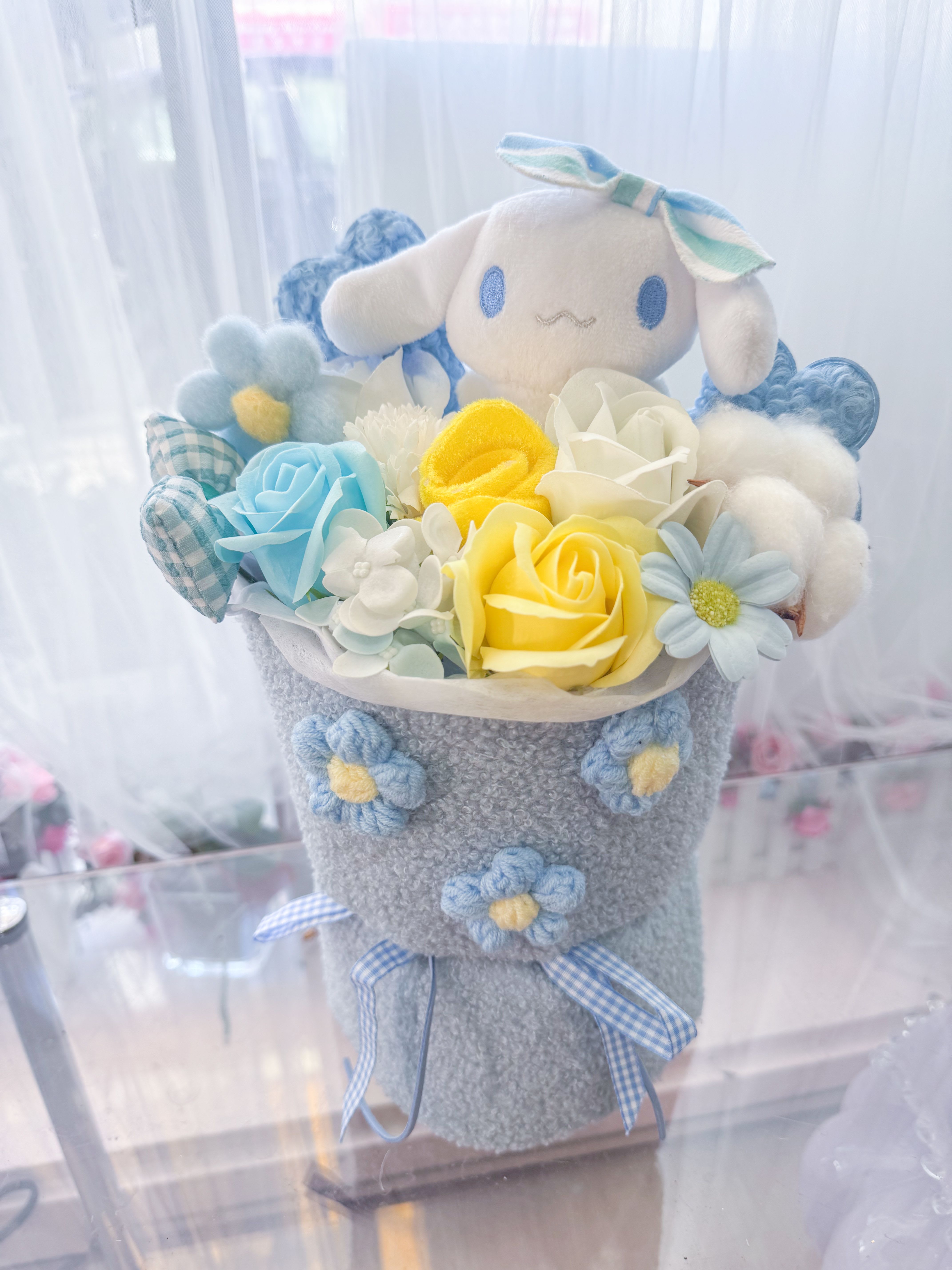 Plush bunny bouquet with pastel roses and daisies in a gray wrap