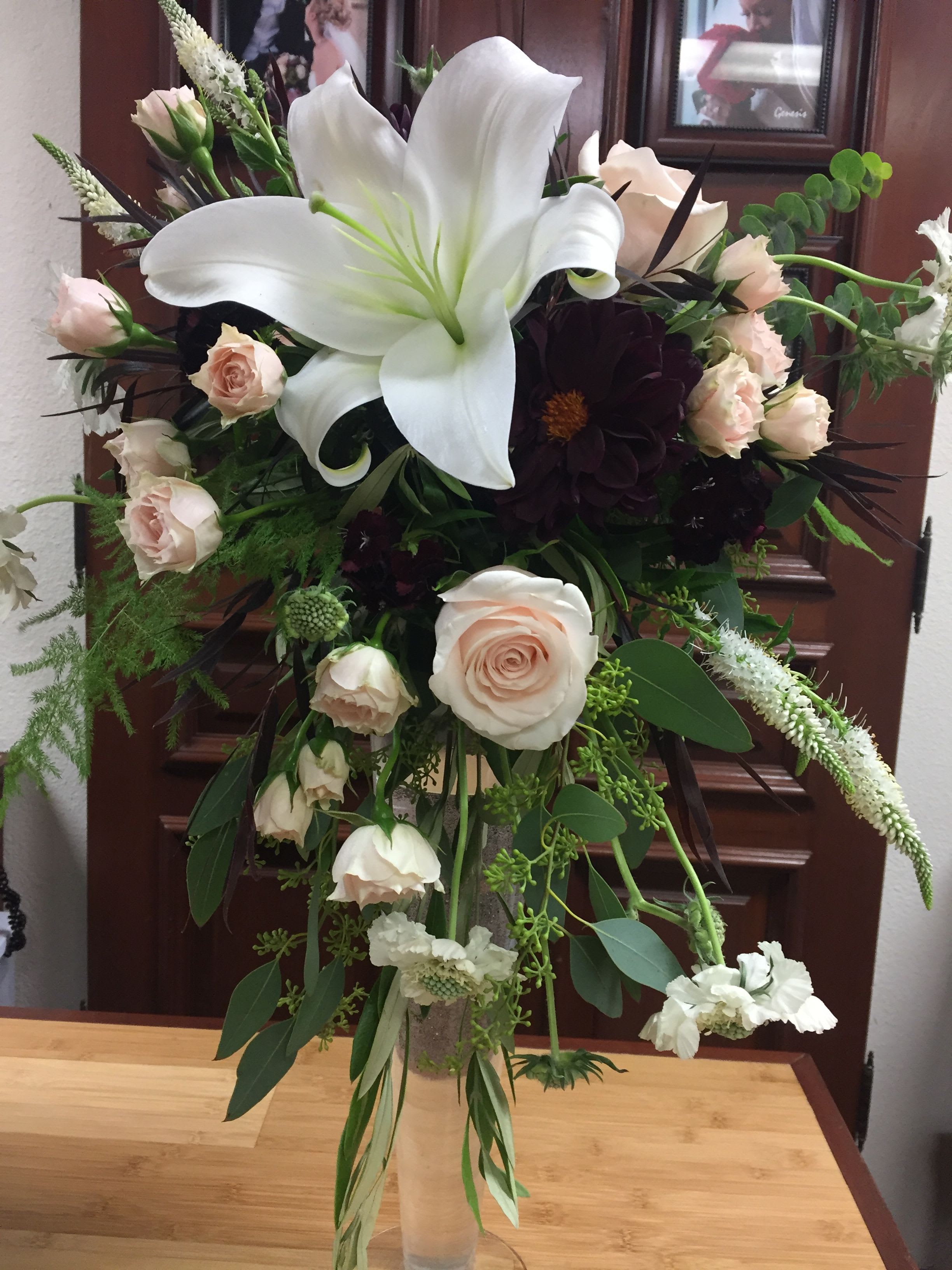Burgundy Bridal Bouquet - This special wedding bouquet includes seasonal dahlias, lilies, roses, lisianthus, and mini roses with greens in a handheld cascading bouquet.