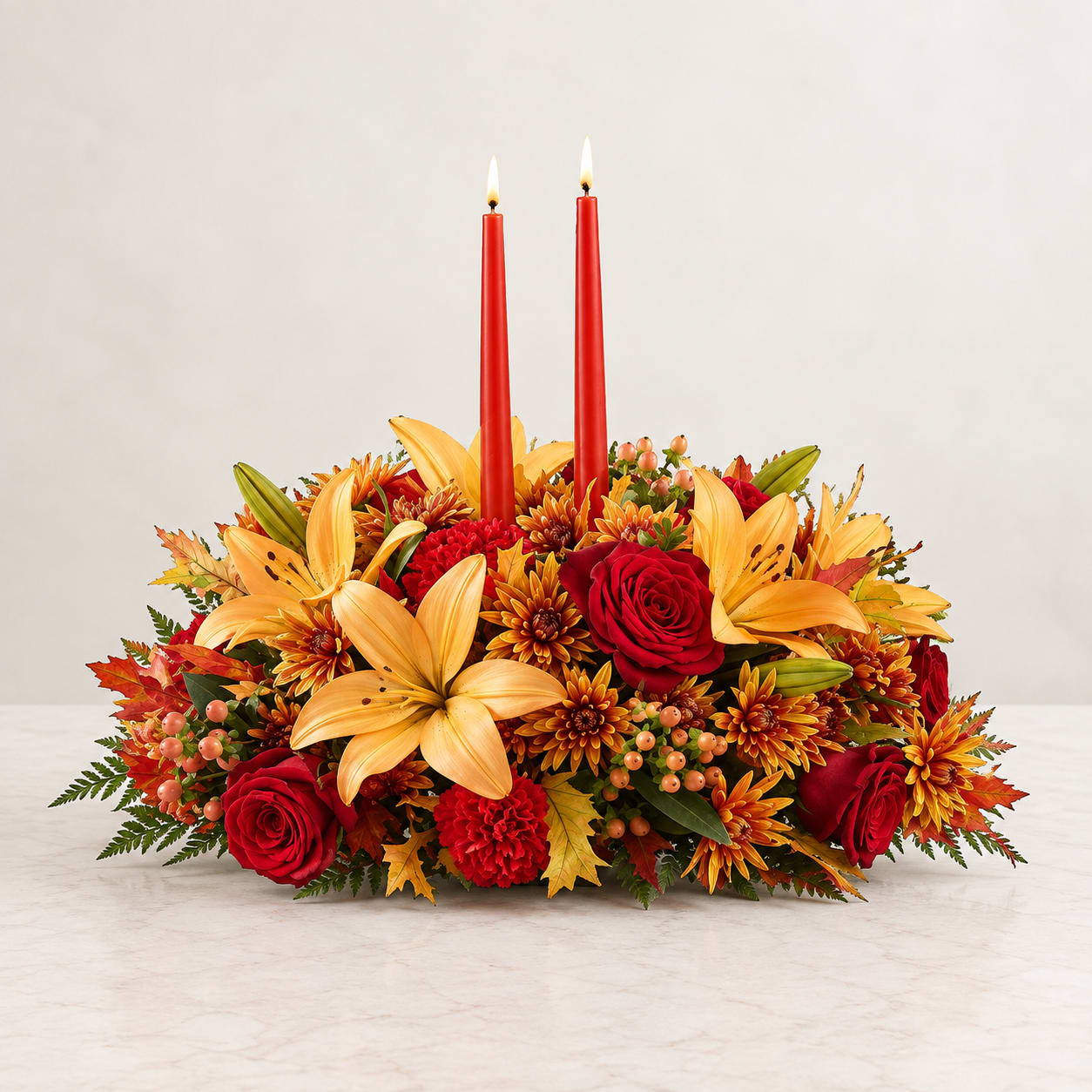 Autumn floral centerpiece with red candles, roses, and lilies