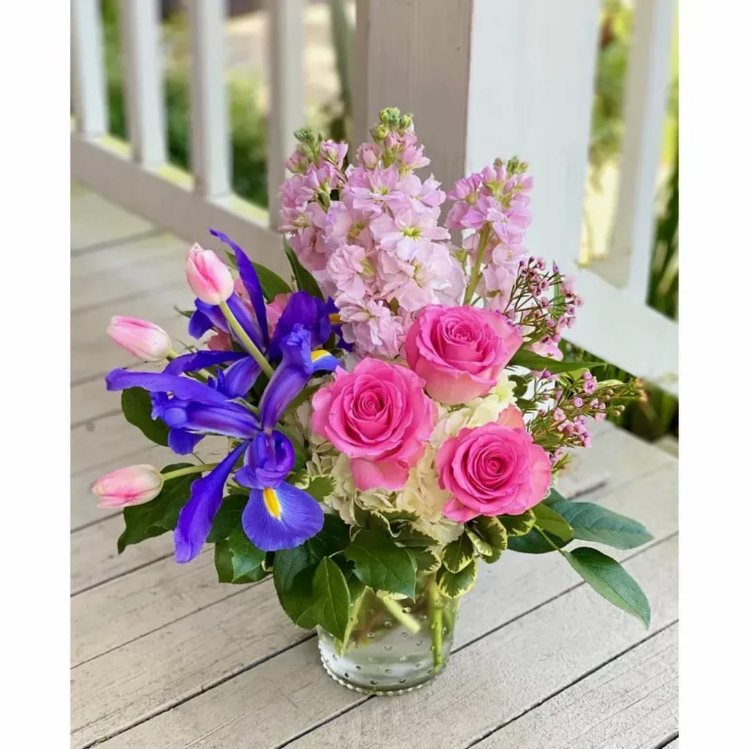 Pink roses and purple irises arranged in a clear glass vase