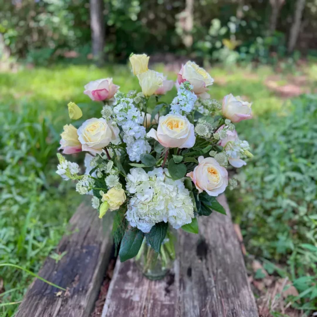 Bouquet of pale roses and white flowers in a clear glass vase