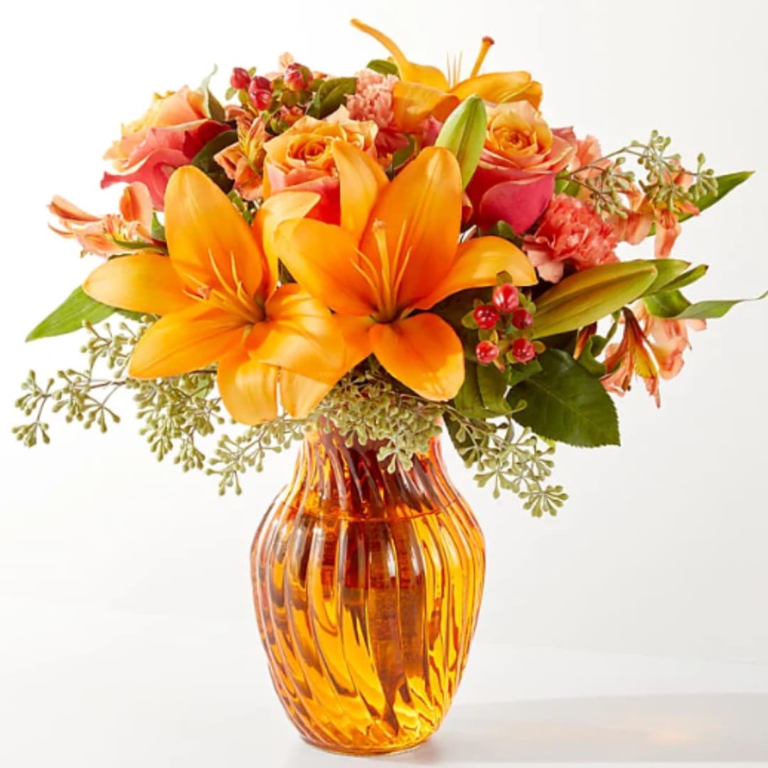 Orange lilies and roses in an amber glass vase