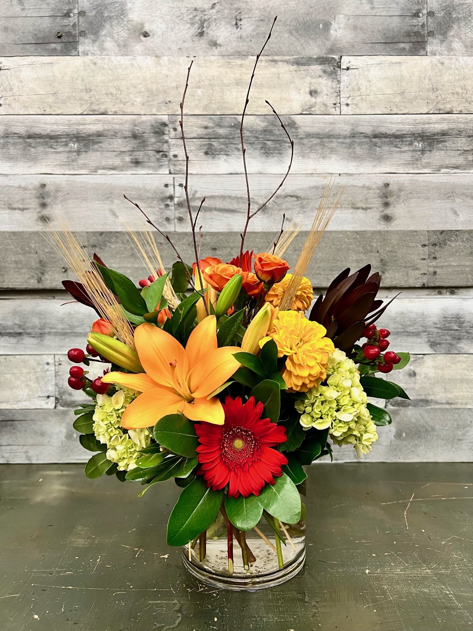 Autumn Day - This lovely mix of fall colors is sure to brighten any area!  Loaded with lilies,  hydrangea, mums, hypericum berries and spray roses with textures of wheat, birch branches and eucalyptus.