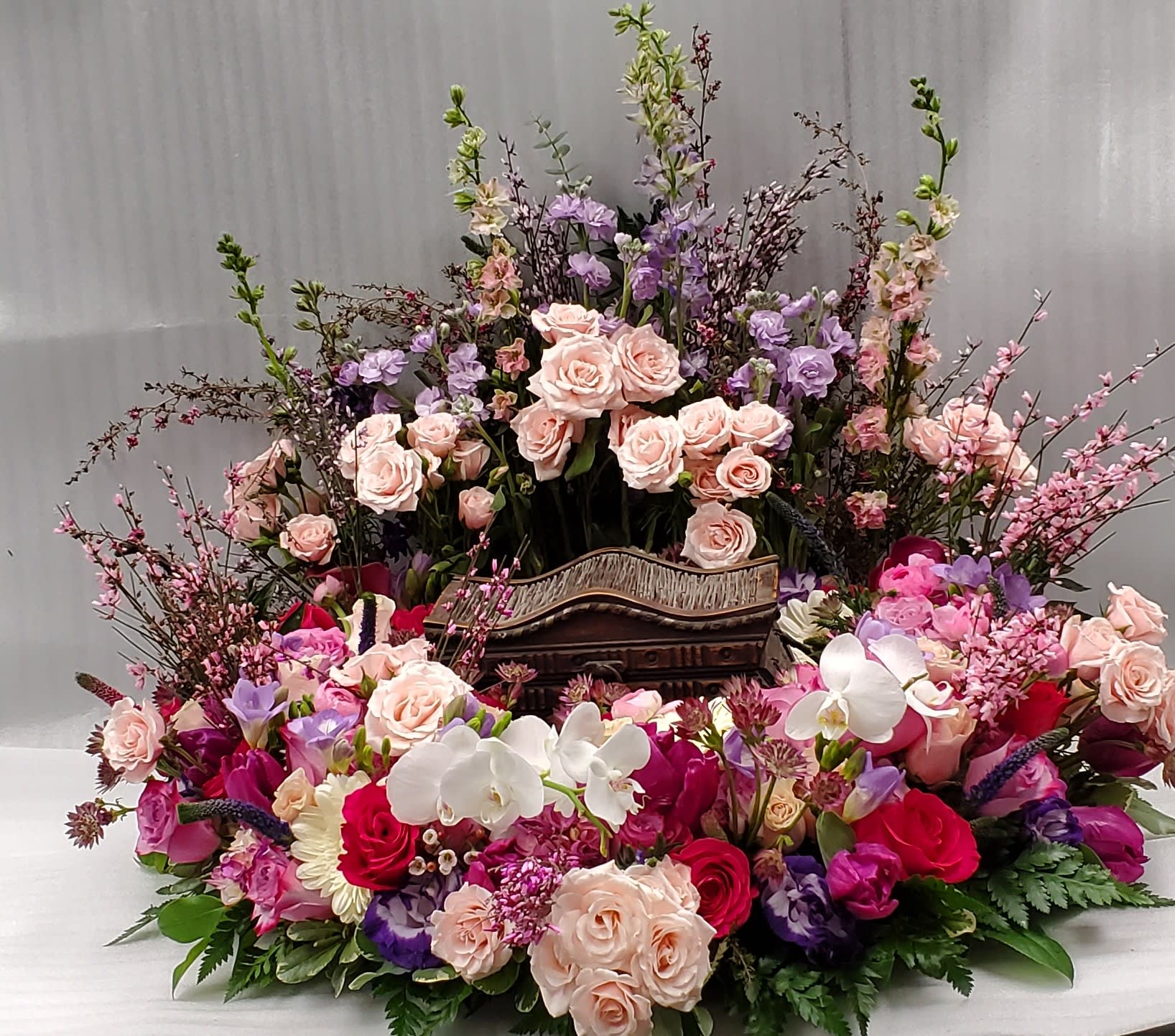 Large floral arrangement with pink and purple roses and white orchids