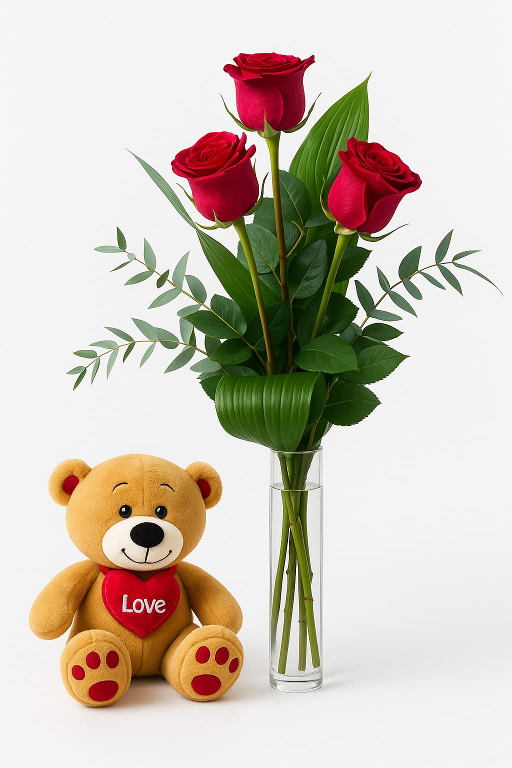 Three red roses in a glass vase beside a teddy bear holding a heart