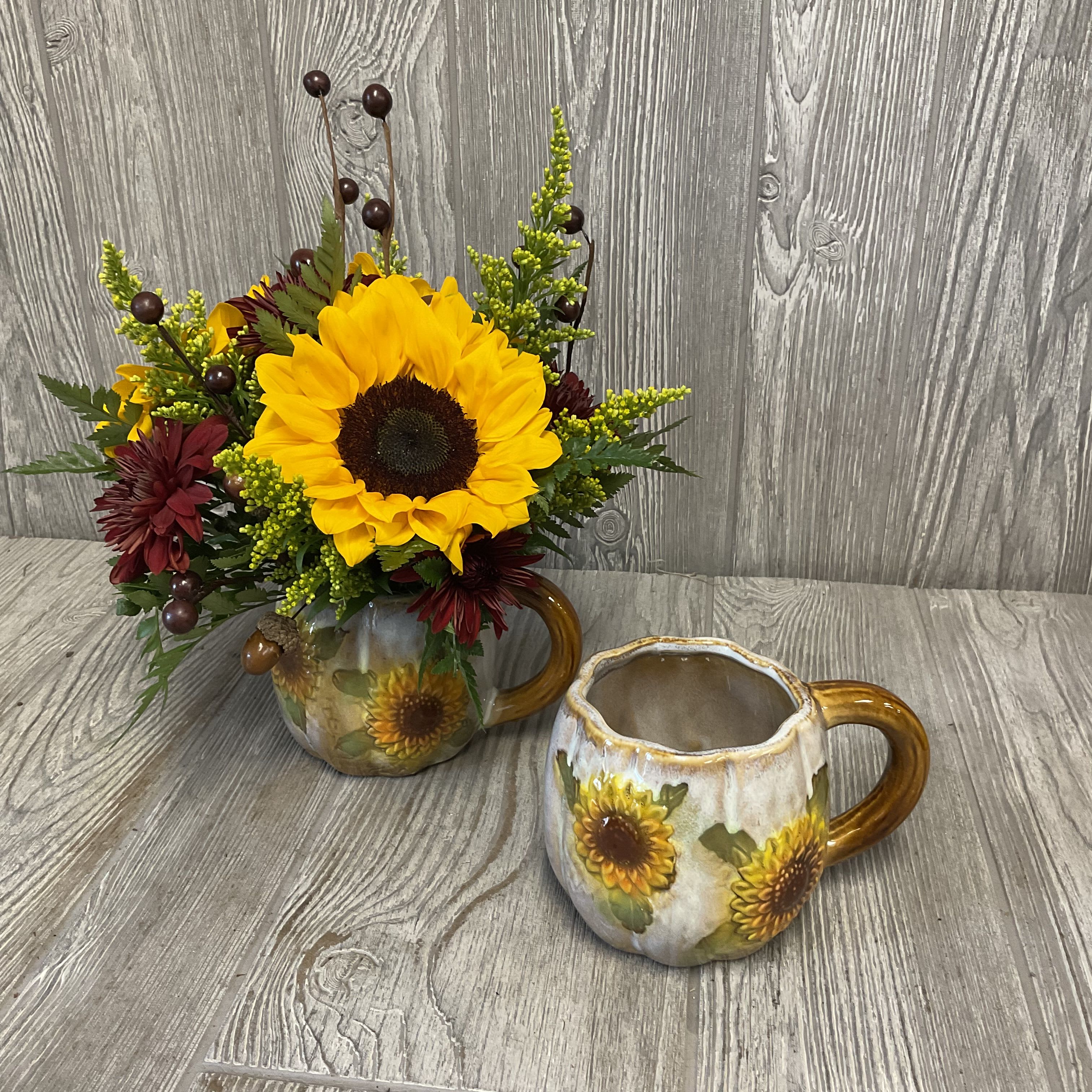 Sunflower arrangement in a sunflower mug beside an empty matching mug