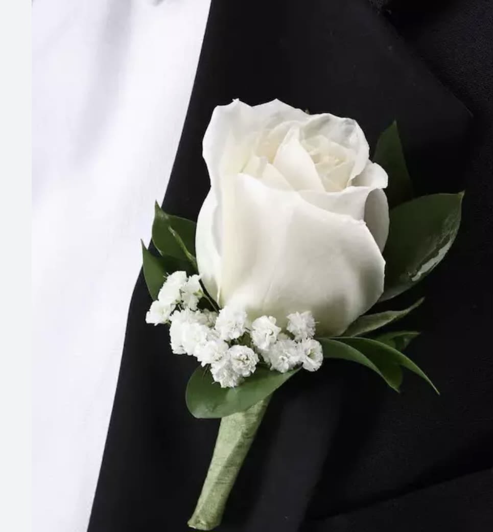 White rose boutonniere with small white filler flowers on a black tuxedo lapel