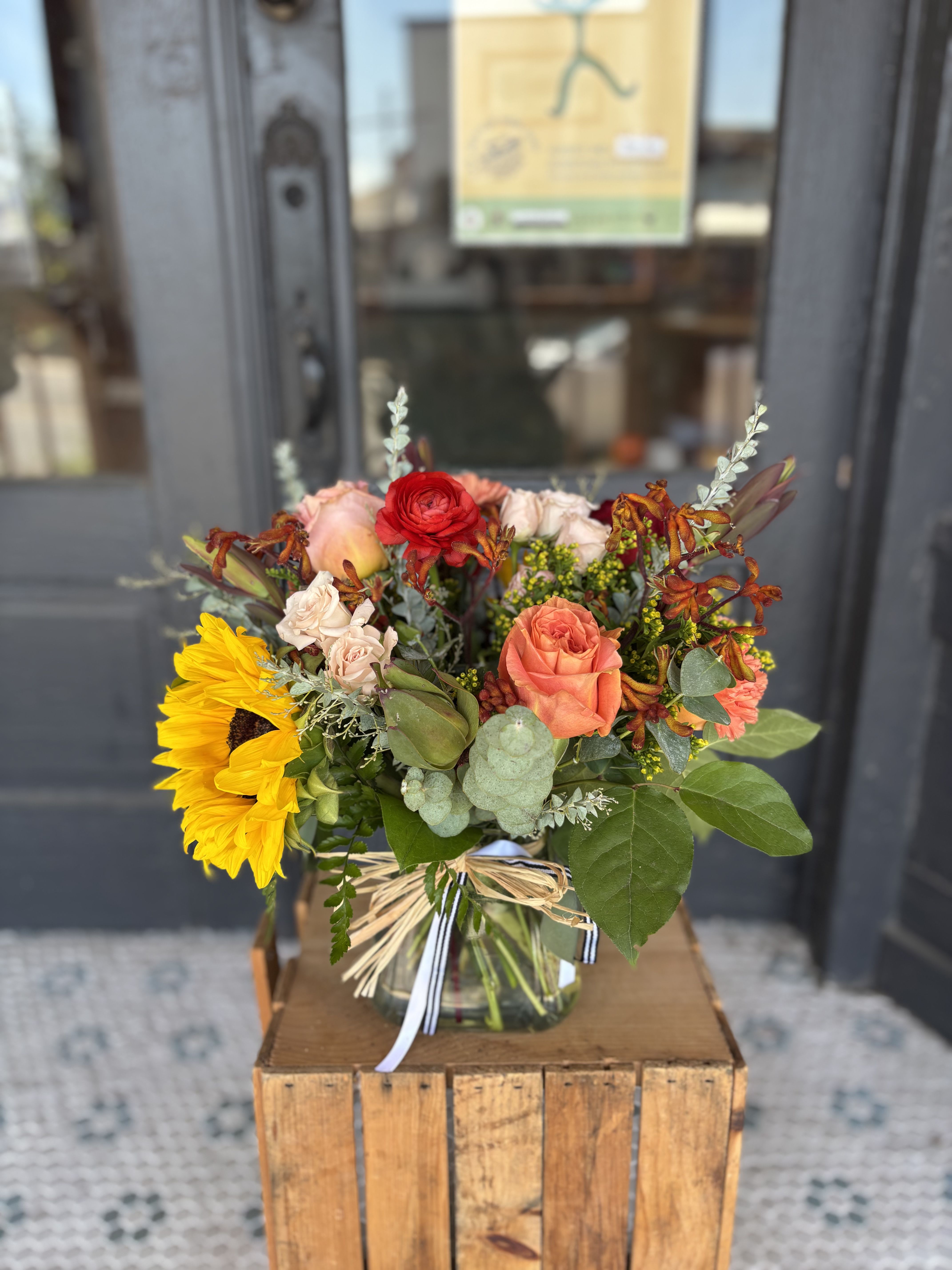 Mixed bouquet in a glass vase with sunflowers and roses