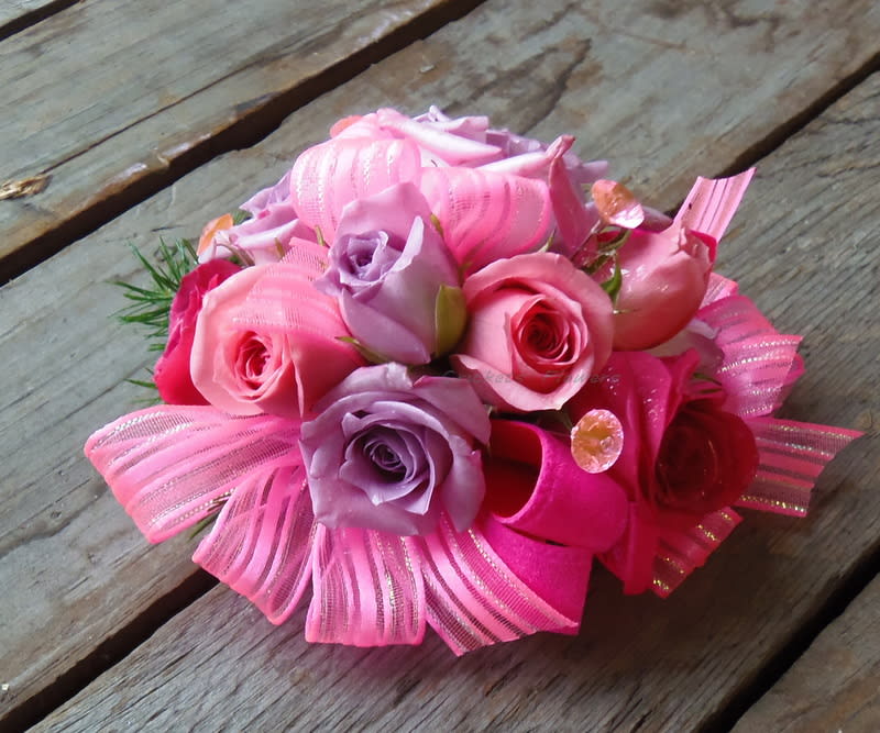 Pink and lavender rose bouquet with ribbon accents on a wooden surface
