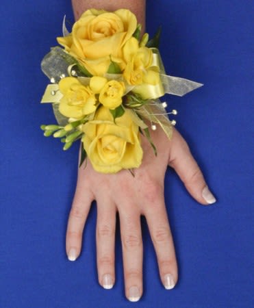 Yellow rose wrist corsage with ribbon on a person's hand