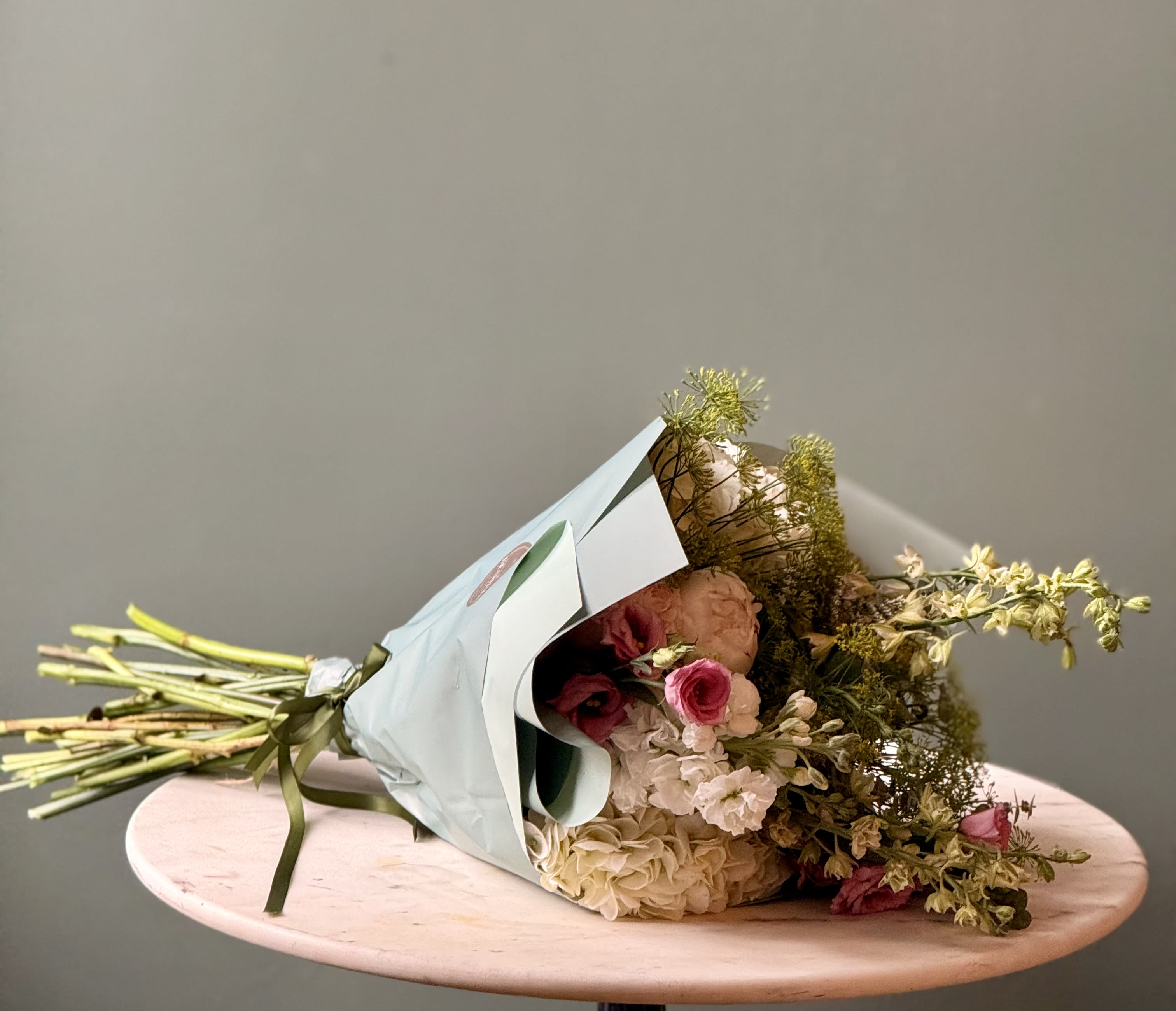 Designer's Choice Wrapped Bouquet - Our Designer's Choice Wrapped Bouquet features a fresh, hand-selected mix of seasonal flowers artfully wrapped and ready to enjoy. Perfect for birthdays, celebrations, thank-you, or just because.  * Available for pickup only.  If you have a preferred color palette, please include it in the Special Instructions at checkout: - Bright &amp; Colorful - Neutrals (shades of pink, white, green)  - White &amp; Green - Blue &amp; White Each bouquet is unique and created with the freshest flowers available. Flower varieties and colors may vary based on seasonal availability.