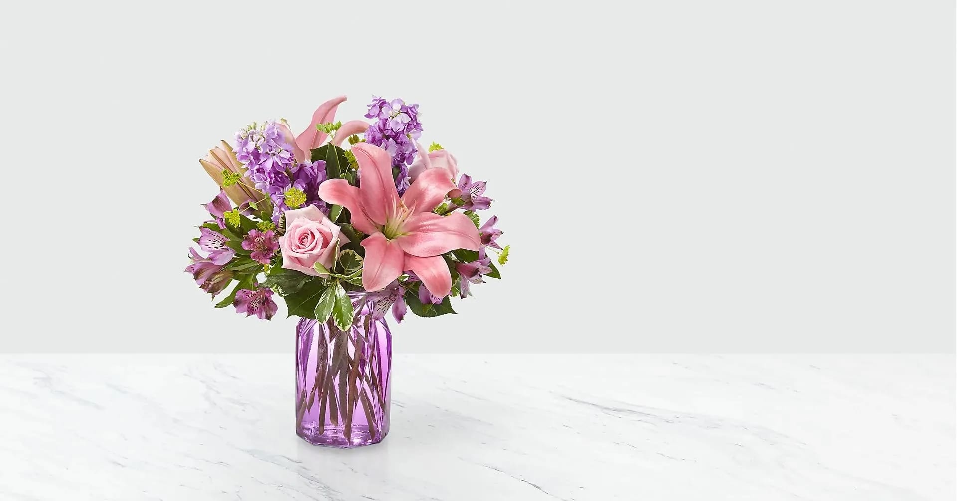 Pink lilies and roses in a purple glass vase