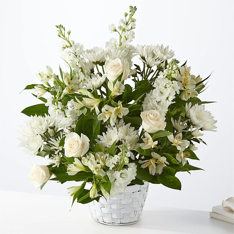 White roses and mixed white flowers in a white basket vase