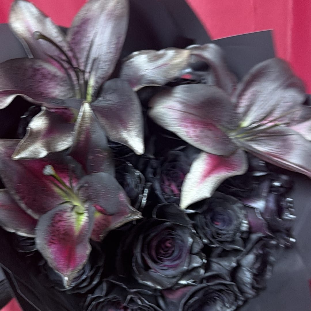 Dark roses and lilies in a black bouquet with pink accents