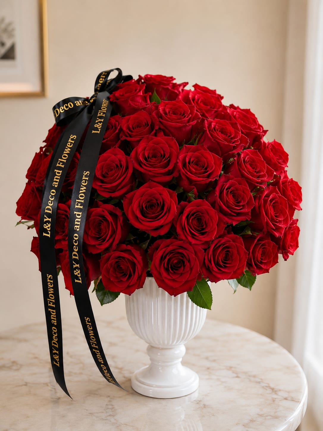 Red rose bouquet in a white pedestal vase with black ribbon