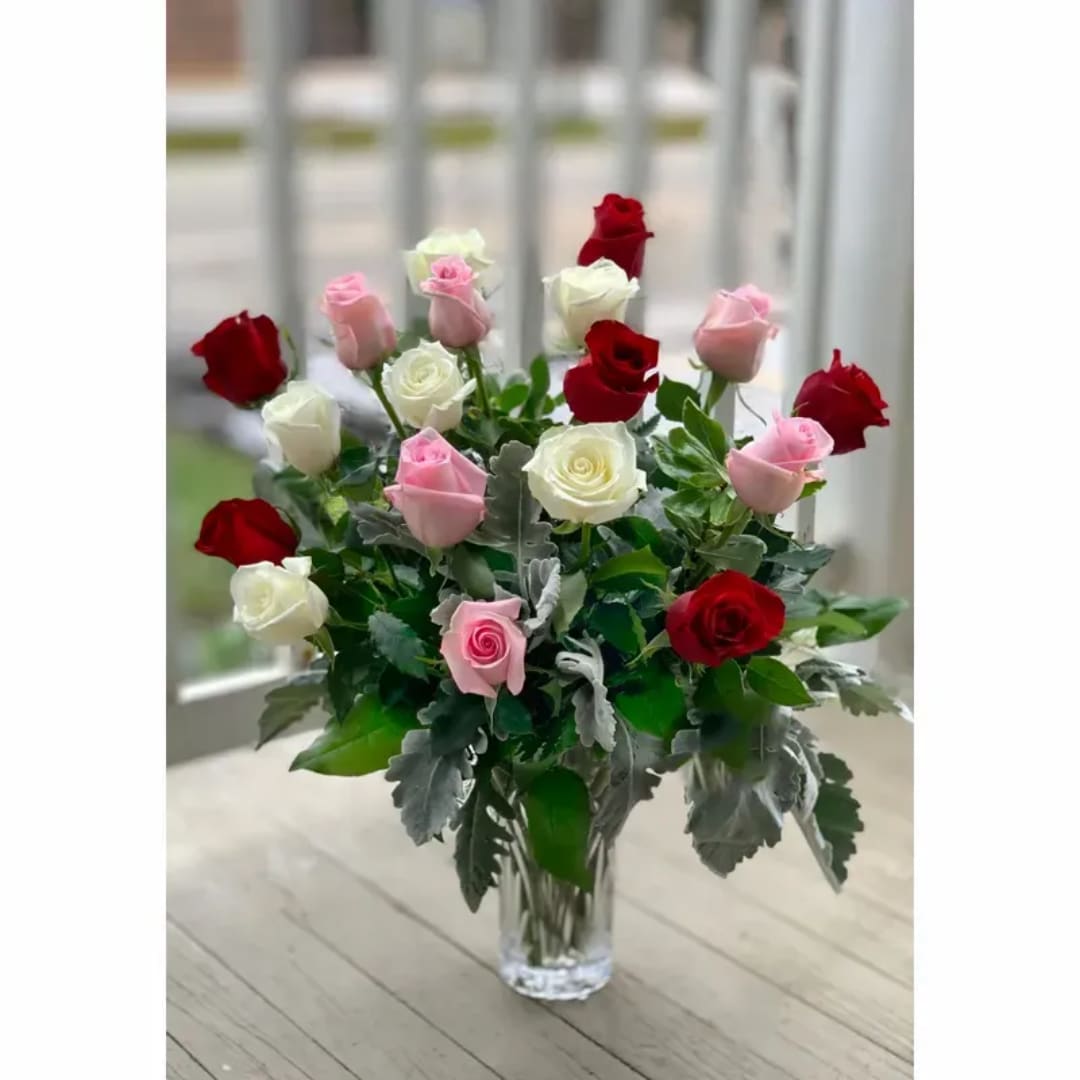 Bouquet of red, pink, and white roses in a clear glass vase