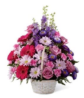 Mixed pink and purple flowers arranged in a white basket