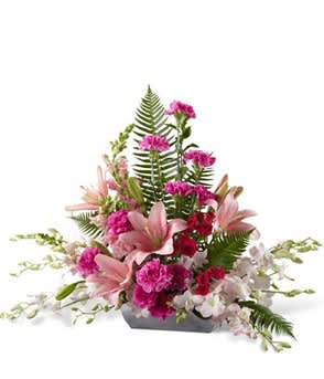 Pink lilies and carnations arranged in a low rectangular container